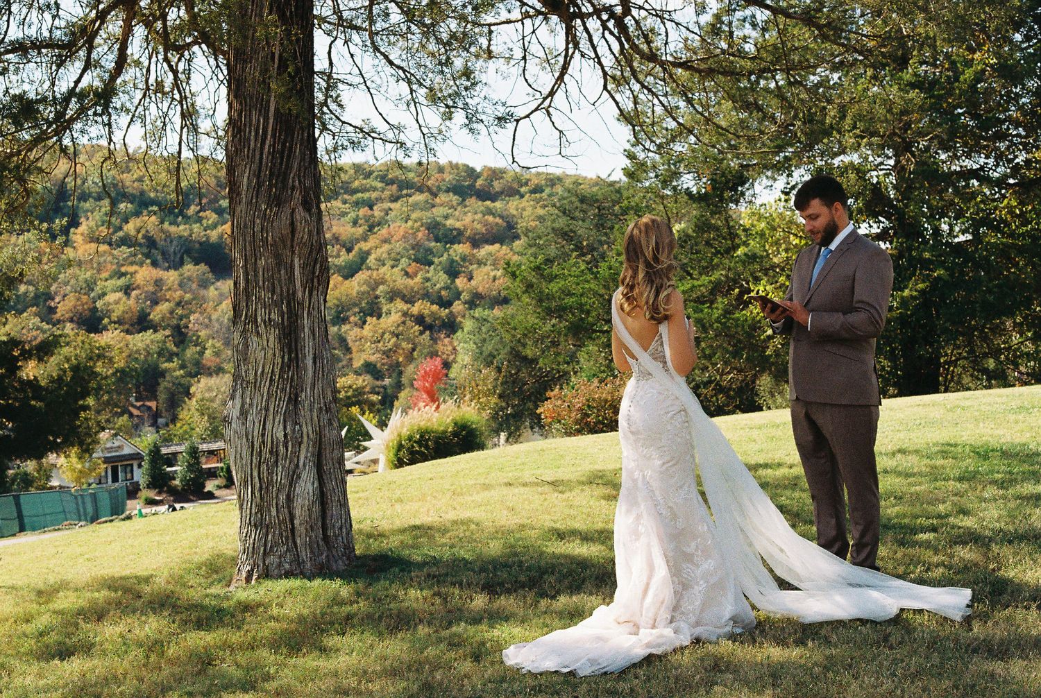 Scenic autumn wedding ceremony outdoors with colorful fall foliage in background.