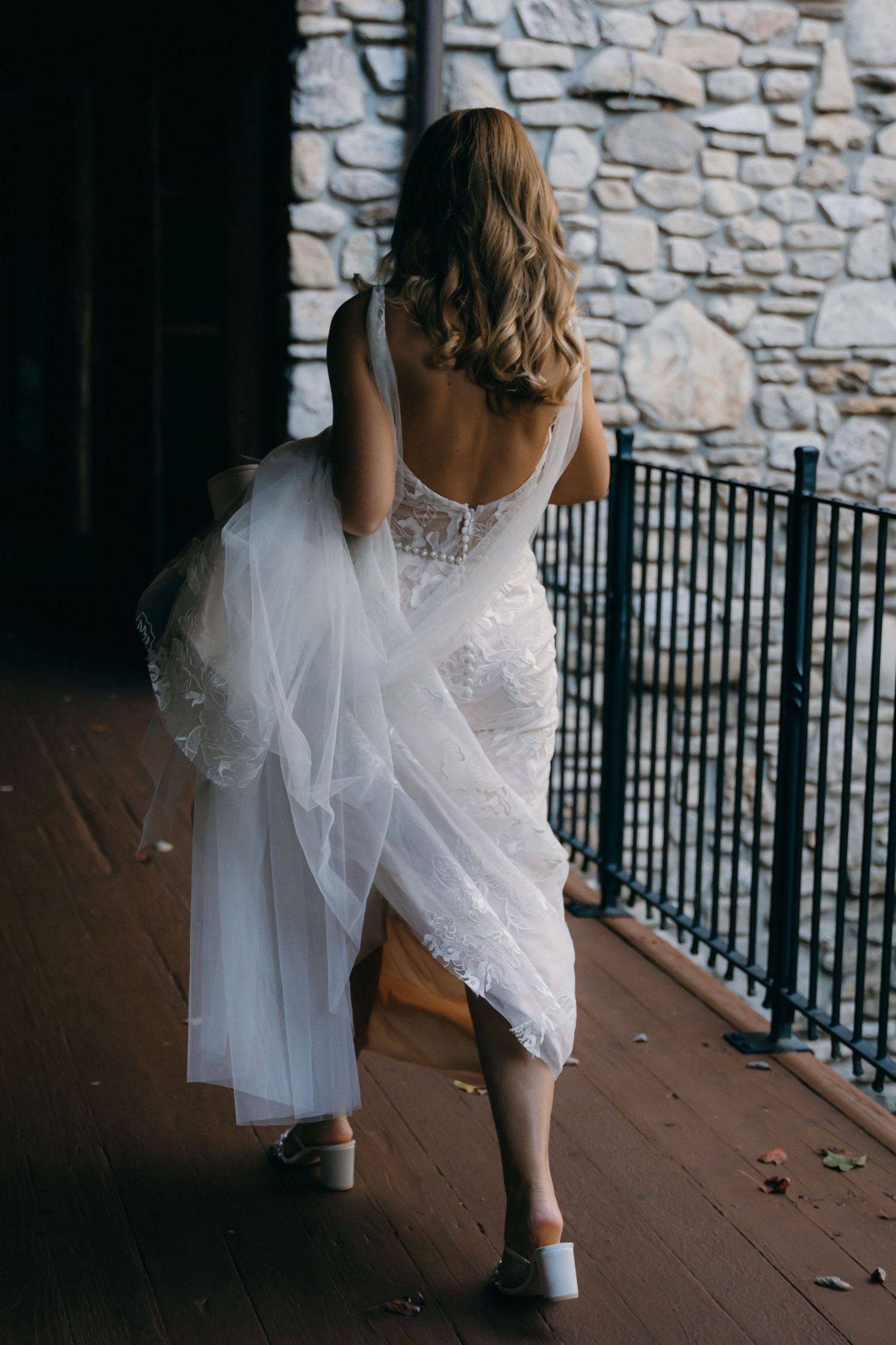 Flowing white dress and boots captured in artistic motion shots on a rustic porch with stone wall backdrop.
