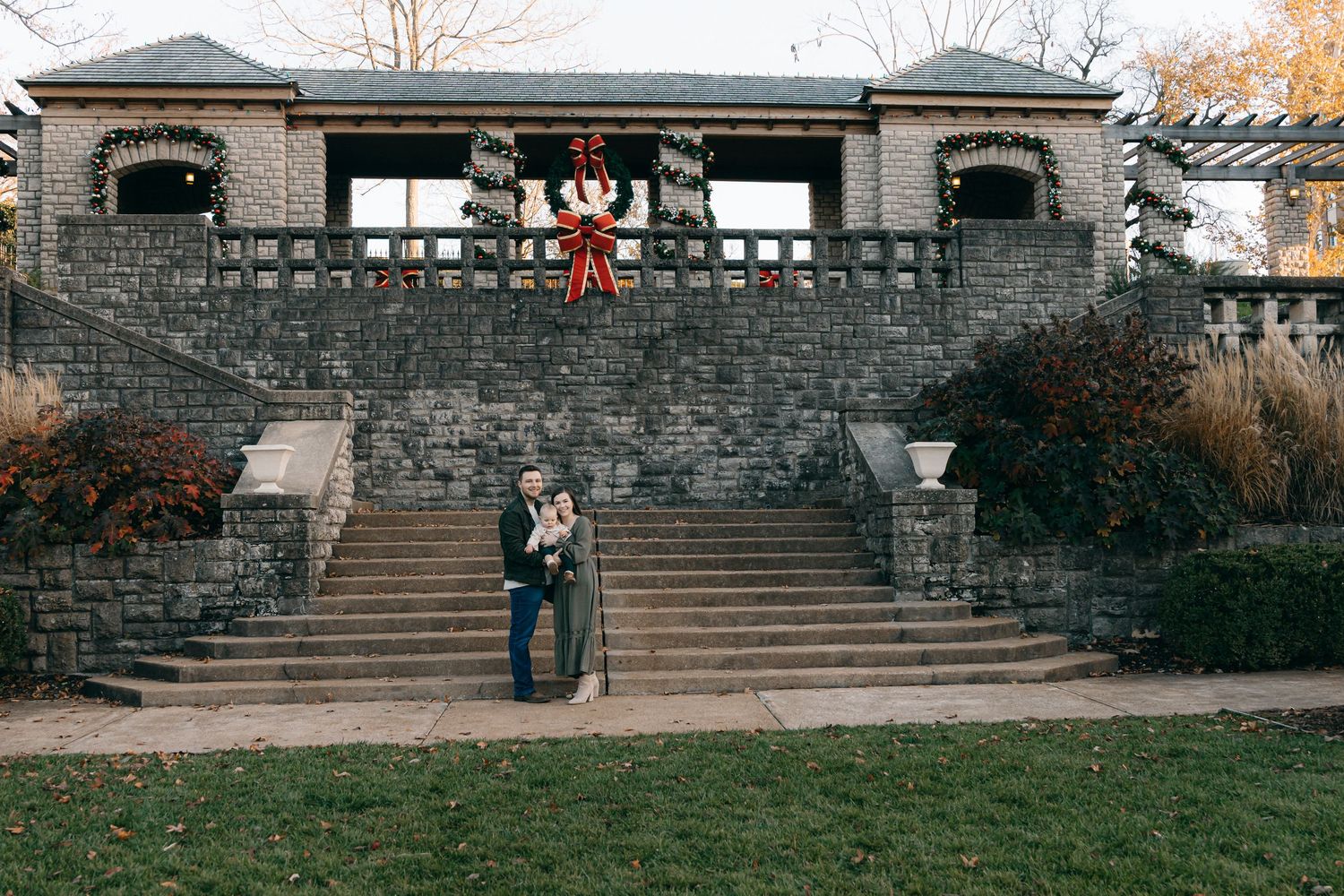 A romantic moment captured at a stone building with decorative holiday wreath.