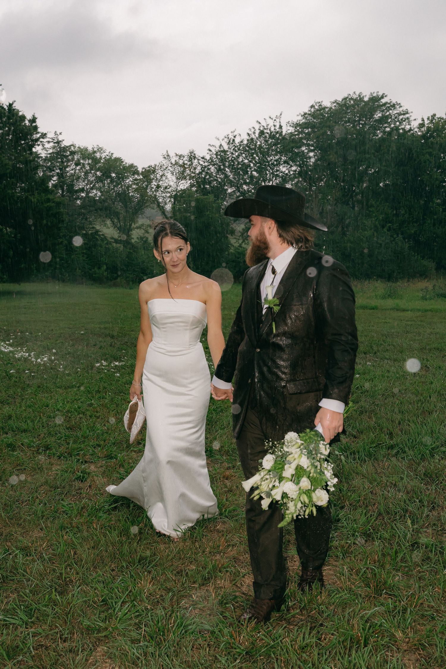 Couple walking through a misty field in formal attire.