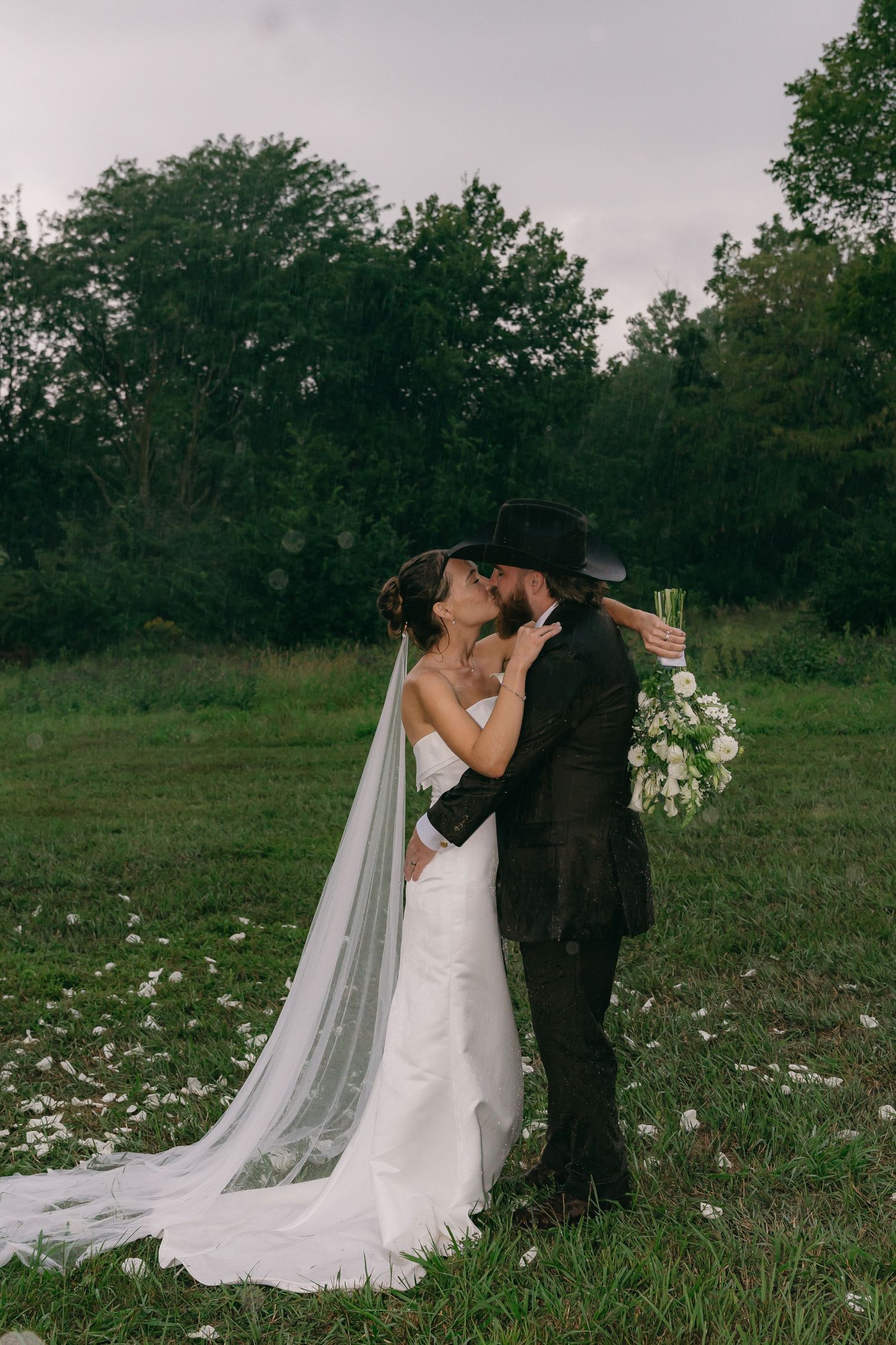 Romantic wedding portrait in a meadow with flowing veil and wildflowers.