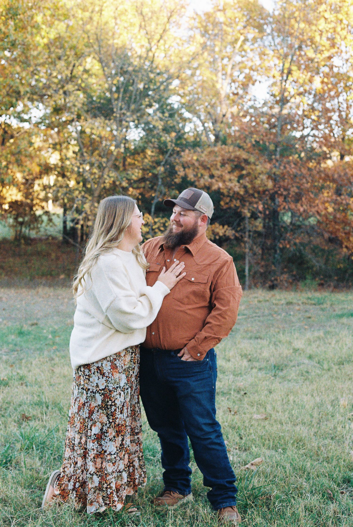 Couple sharing intimate moment in autumn field with golden foliage background.