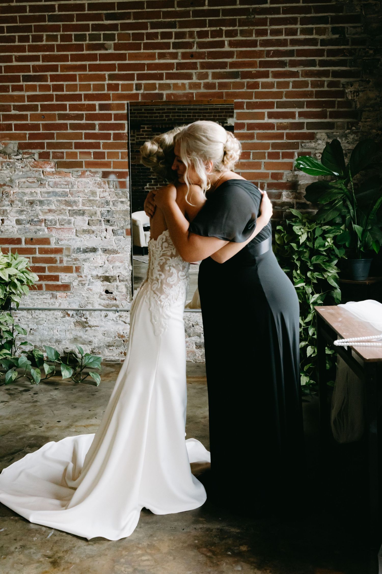 A romantic first look moment between newlyweds against a rustic brick wall backdrop.