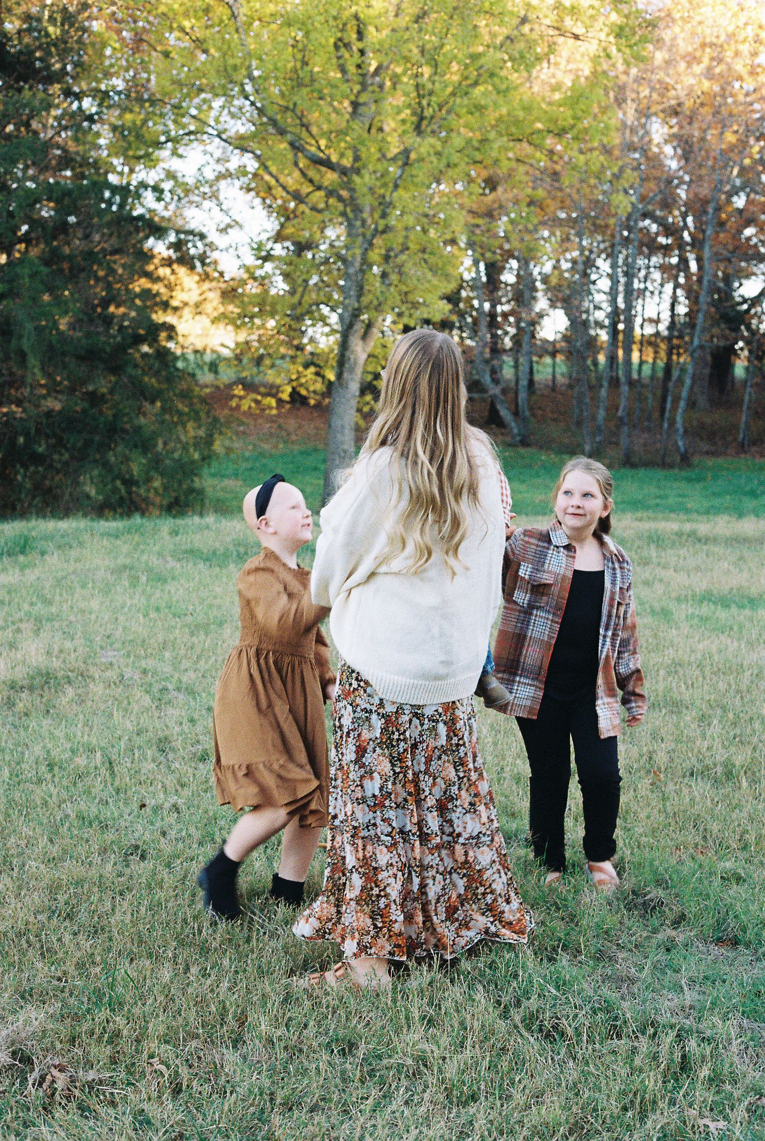 Candid outdoor family moment in autumn field with golden sunlight.