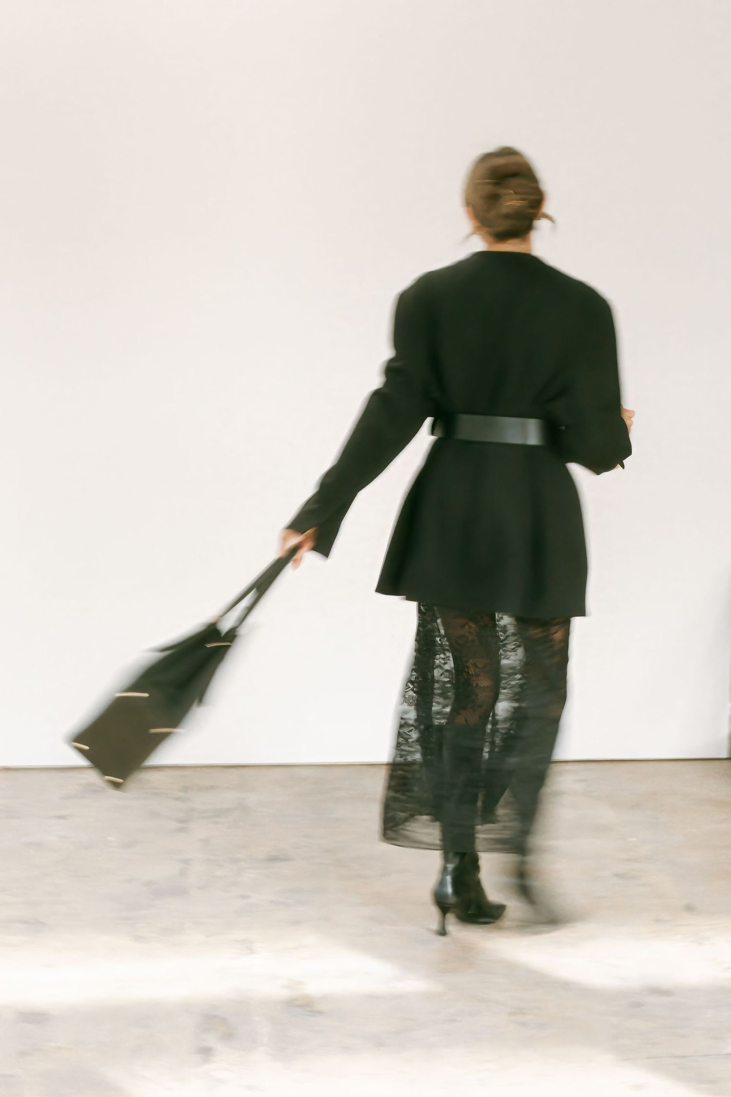 A sequence of motion blur photographs shows a person in black clothing spinning and moving across a white studio space.