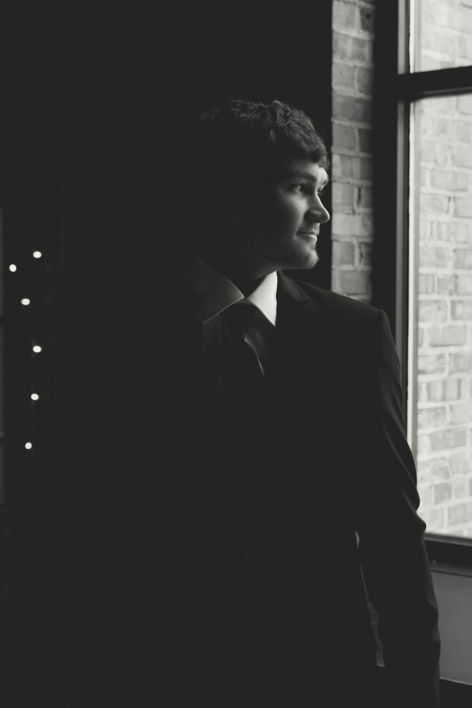 Dramatic silhouette portraits against a brick wall with window lighting.
