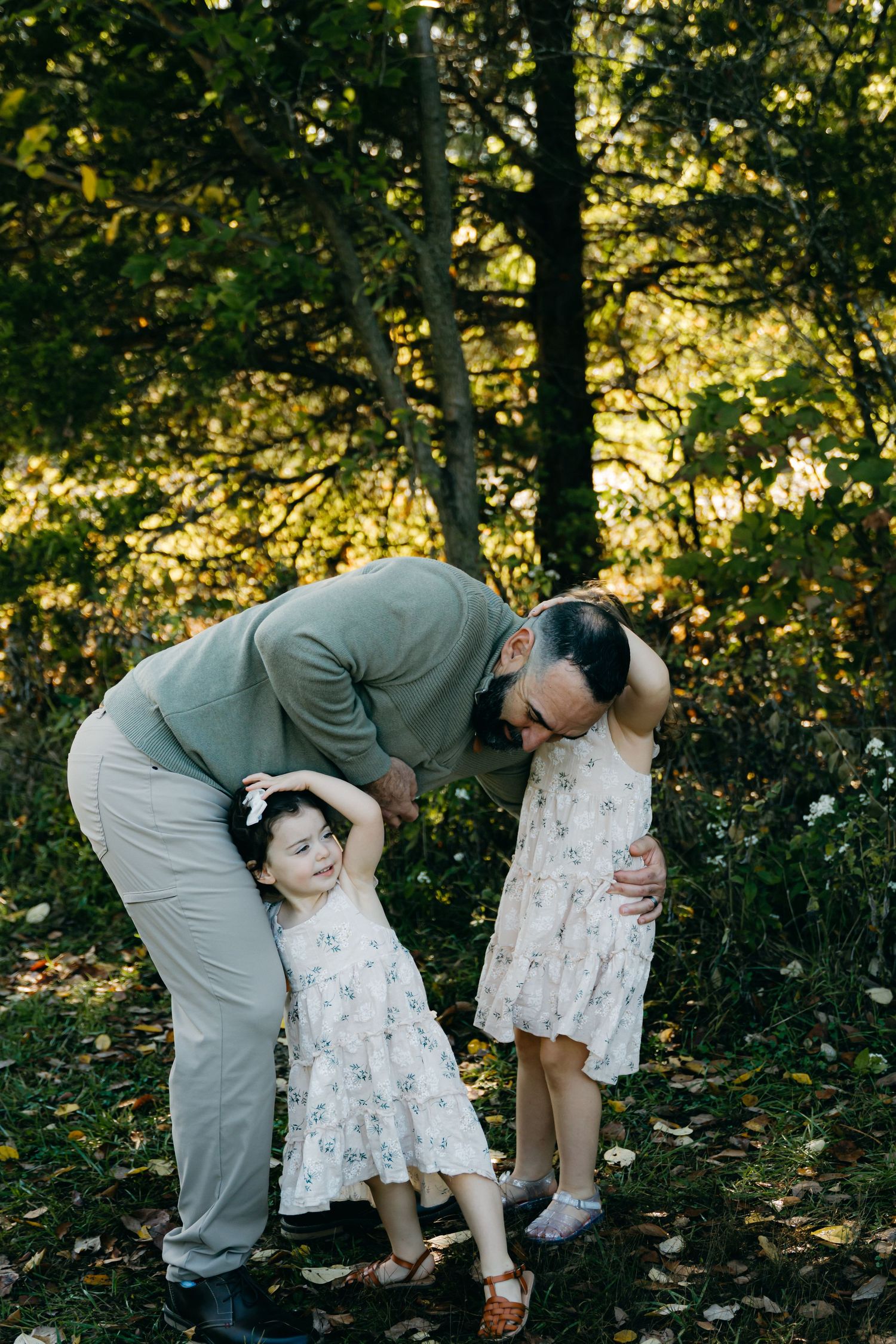 A touching family moment captured in a wooded setting with matching floral dresses.