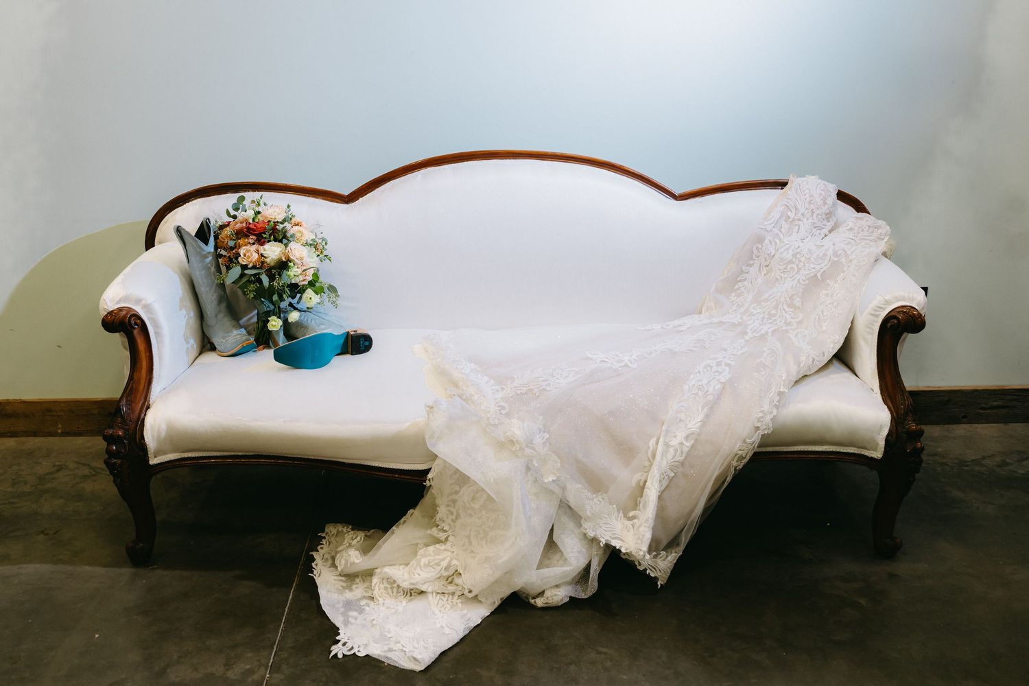 Wedding dress elegantly draped across vintage white chaise lounge furniture.