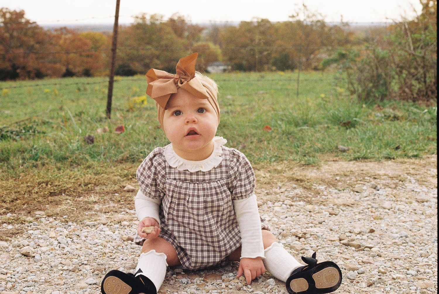 Gingham romper and bow outfit styled for fall outdoor photography.