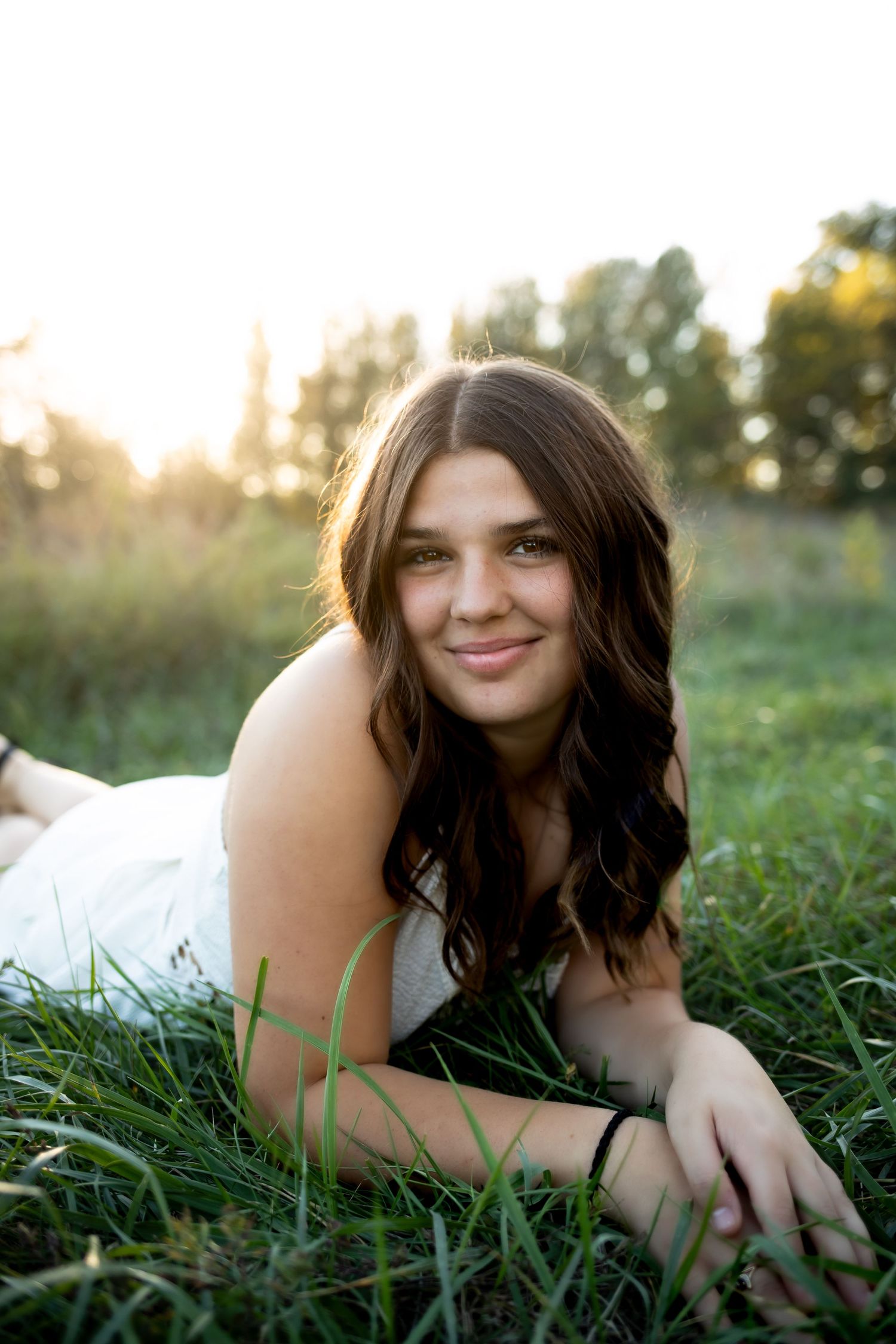 Person laying in green grass during golden hour sunset with natural outdoor lighting.