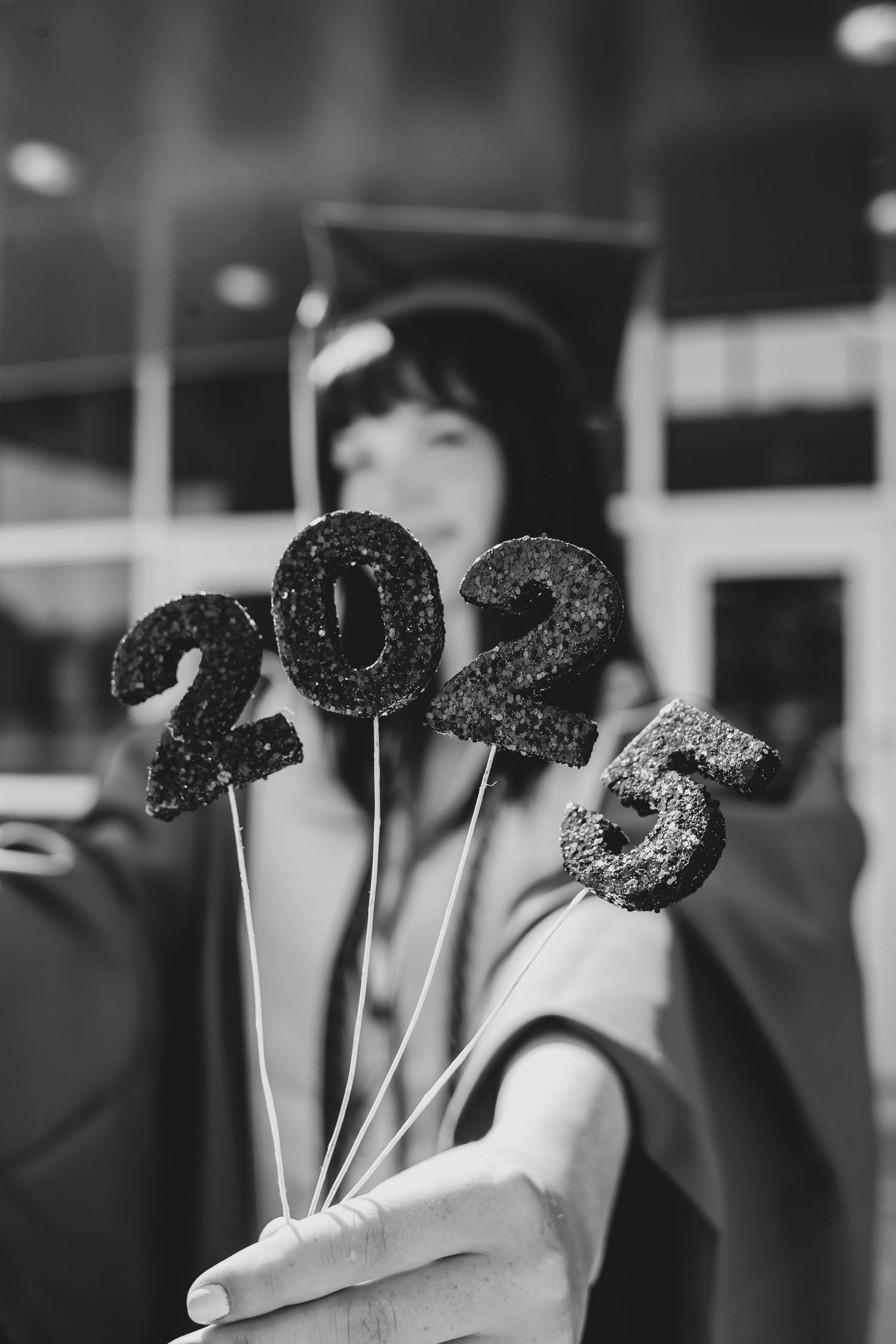 Black and white image showing glittery letters on sticks arranged in a row against a blurred background.