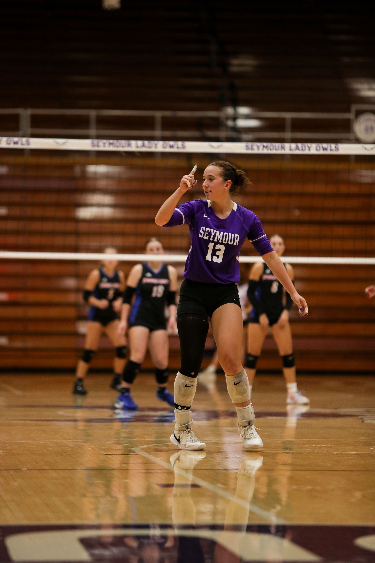 Volleyball player in purple Seymour jersey celebrates on the court during an indoor match.