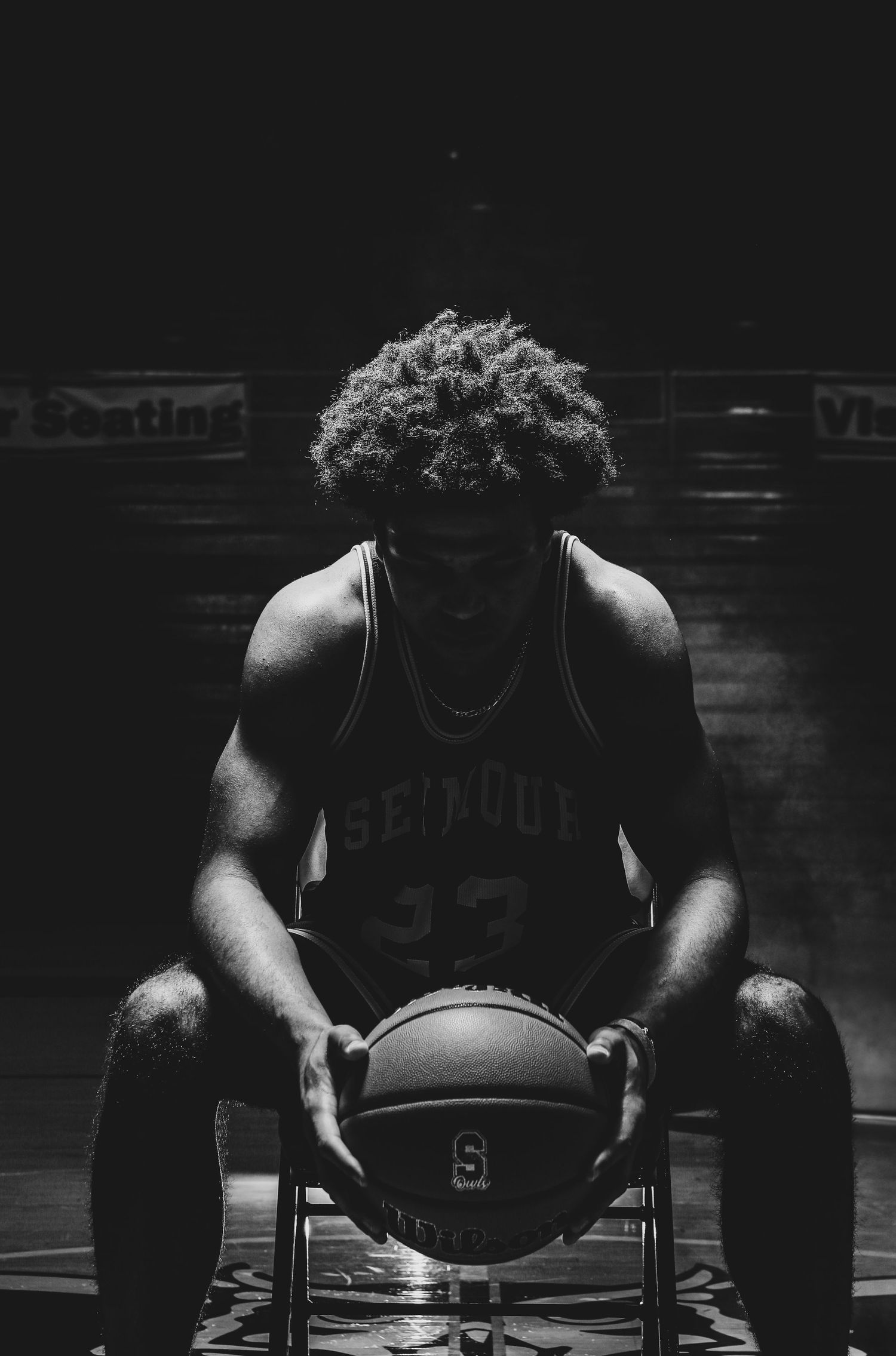 Black and white sequence of a basketball player preparing for a game in dramatic lighting.