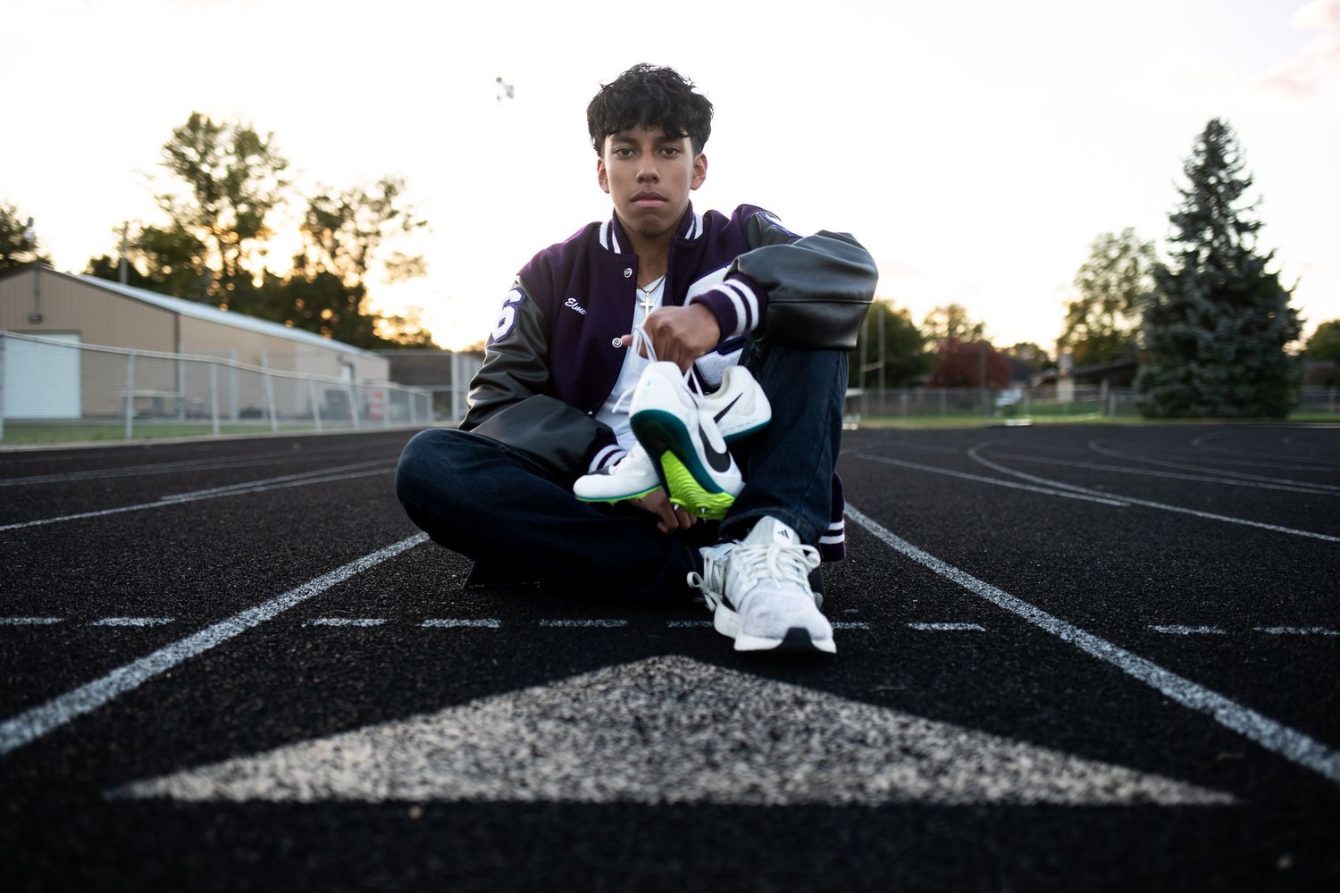 A runner stretches and prepares for training on a dark track at sunset.