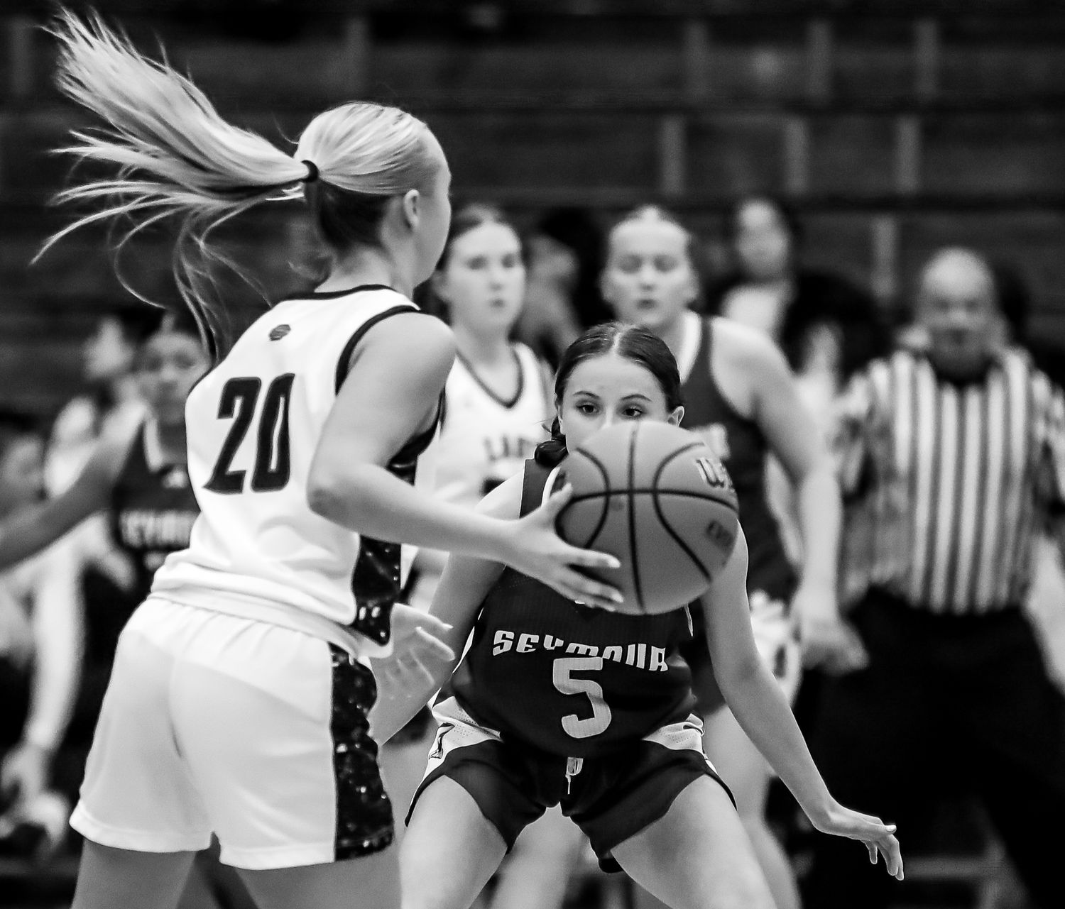 Black and white basketball action photo showing players competing for possession during an intense game.