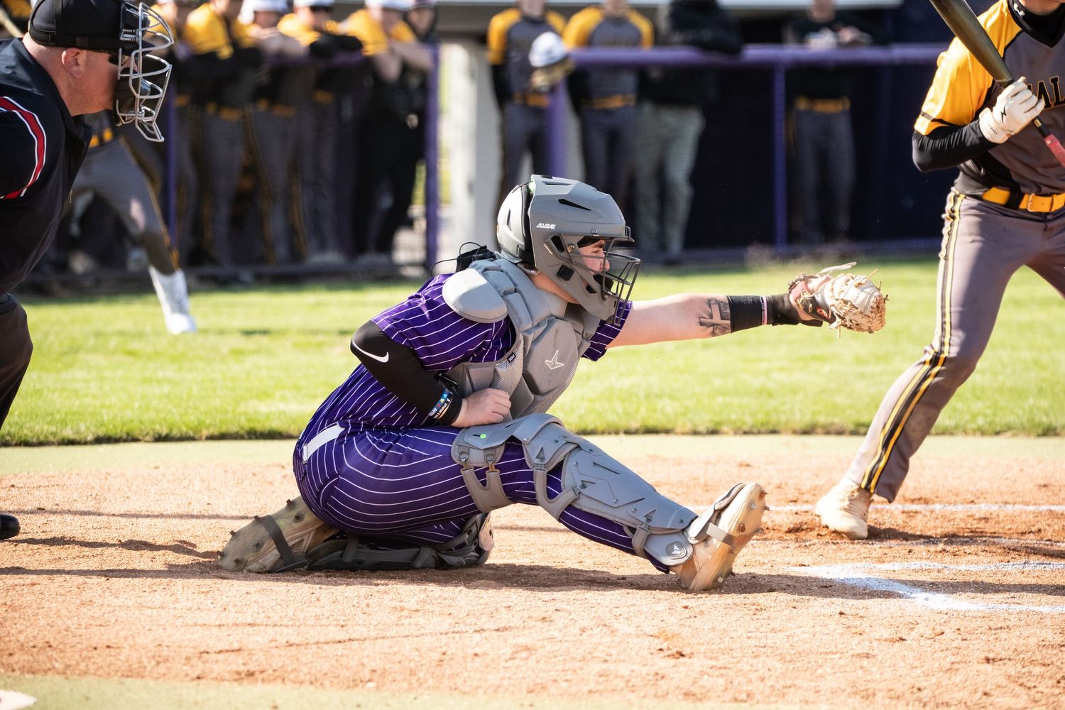 Baseball player catches pitch at home plate during intense game.