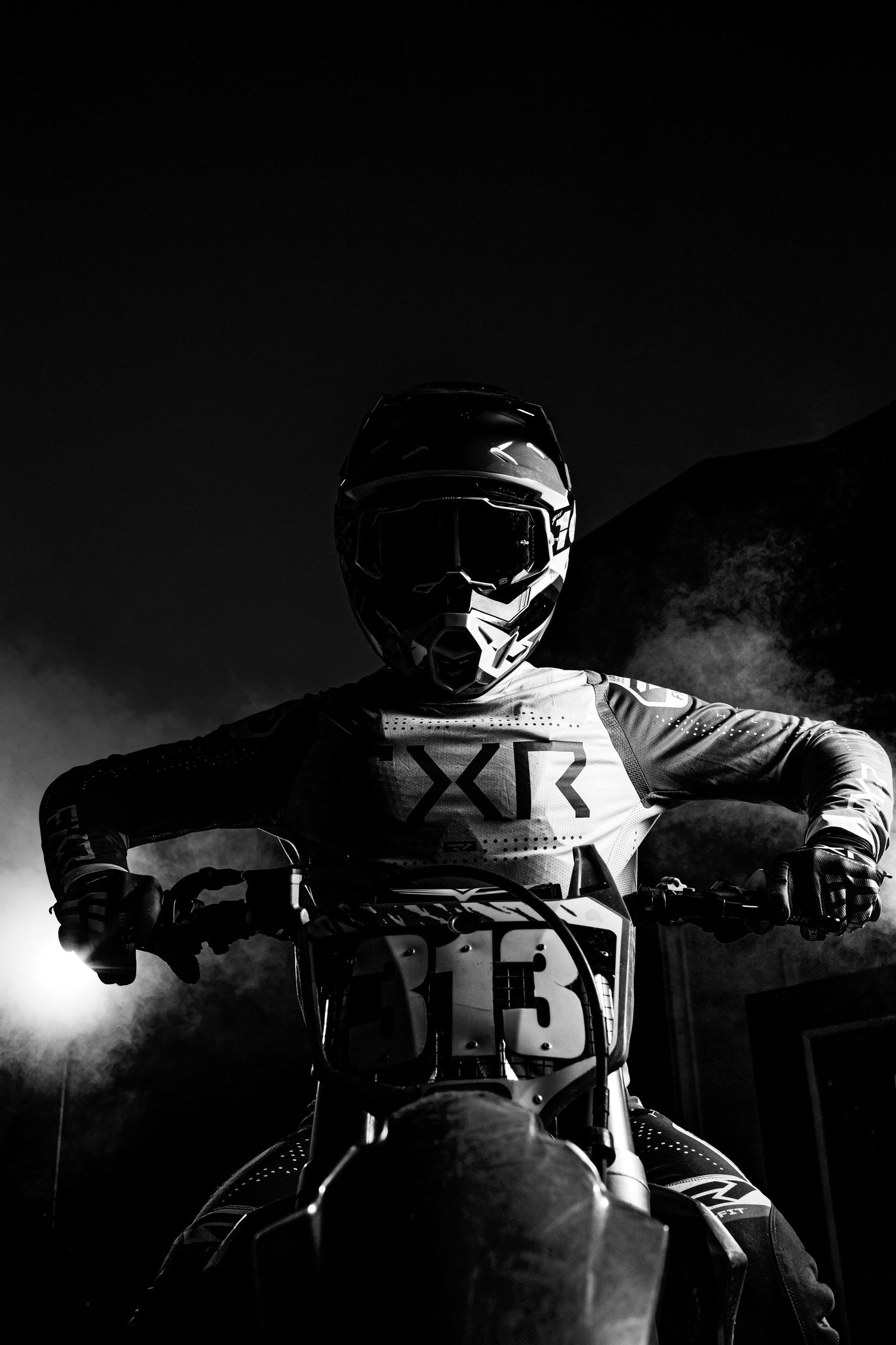 A dramatic black and white panoramic sequence showing motorcycle racing helmets silhouetted against a dark background.