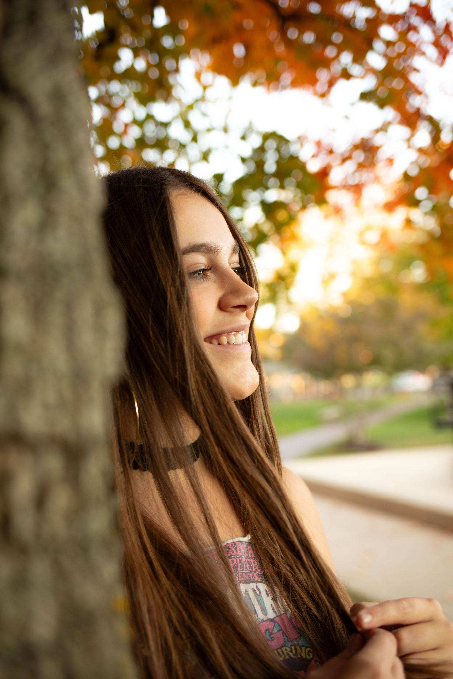A sequence of outdoor portraits capturing long brown hair flowing in autumn sunlight with golden bokeh and tree backdrop.
