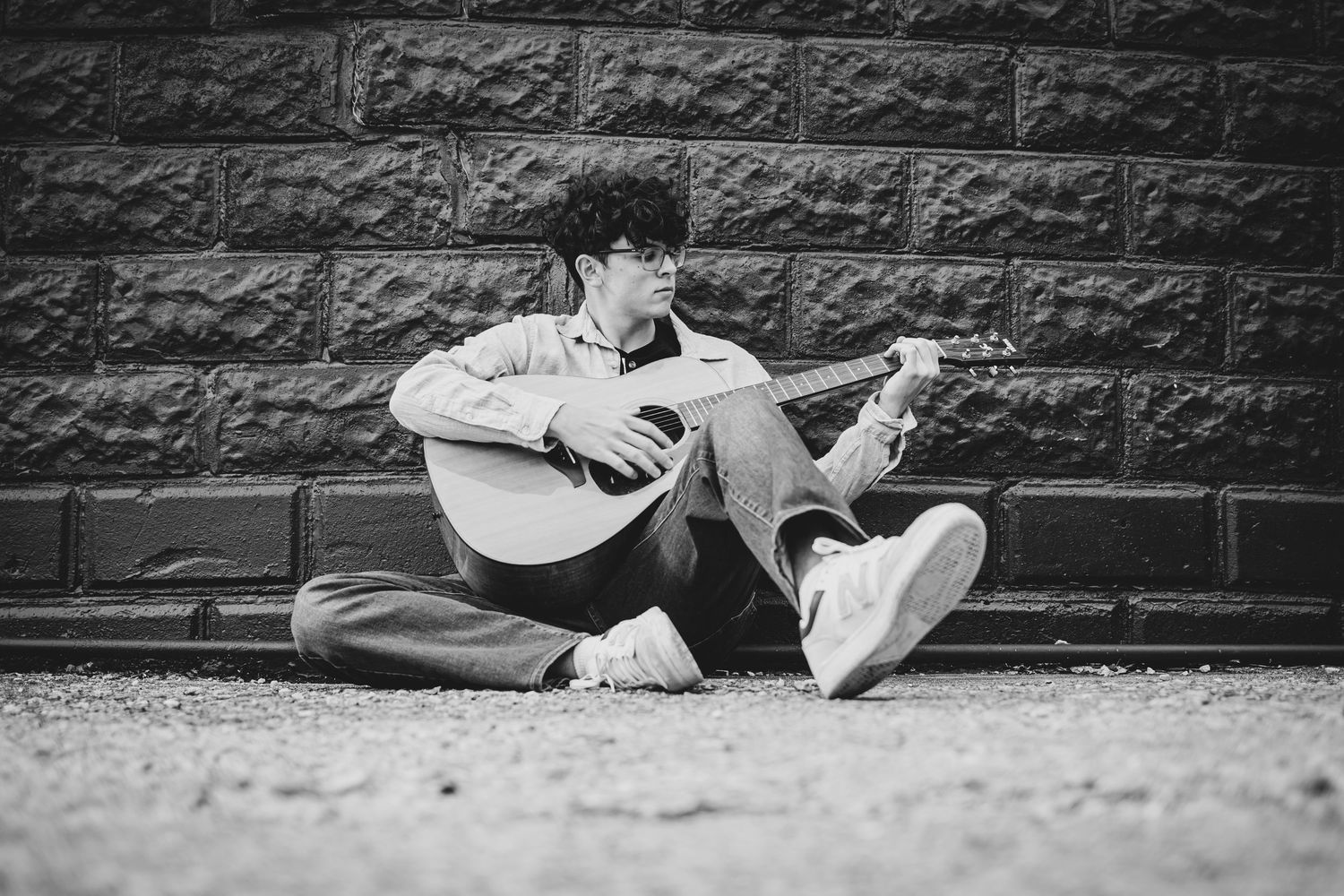 A series of black and white photographs showing a person lying against a stone wall in various artistic poses.
