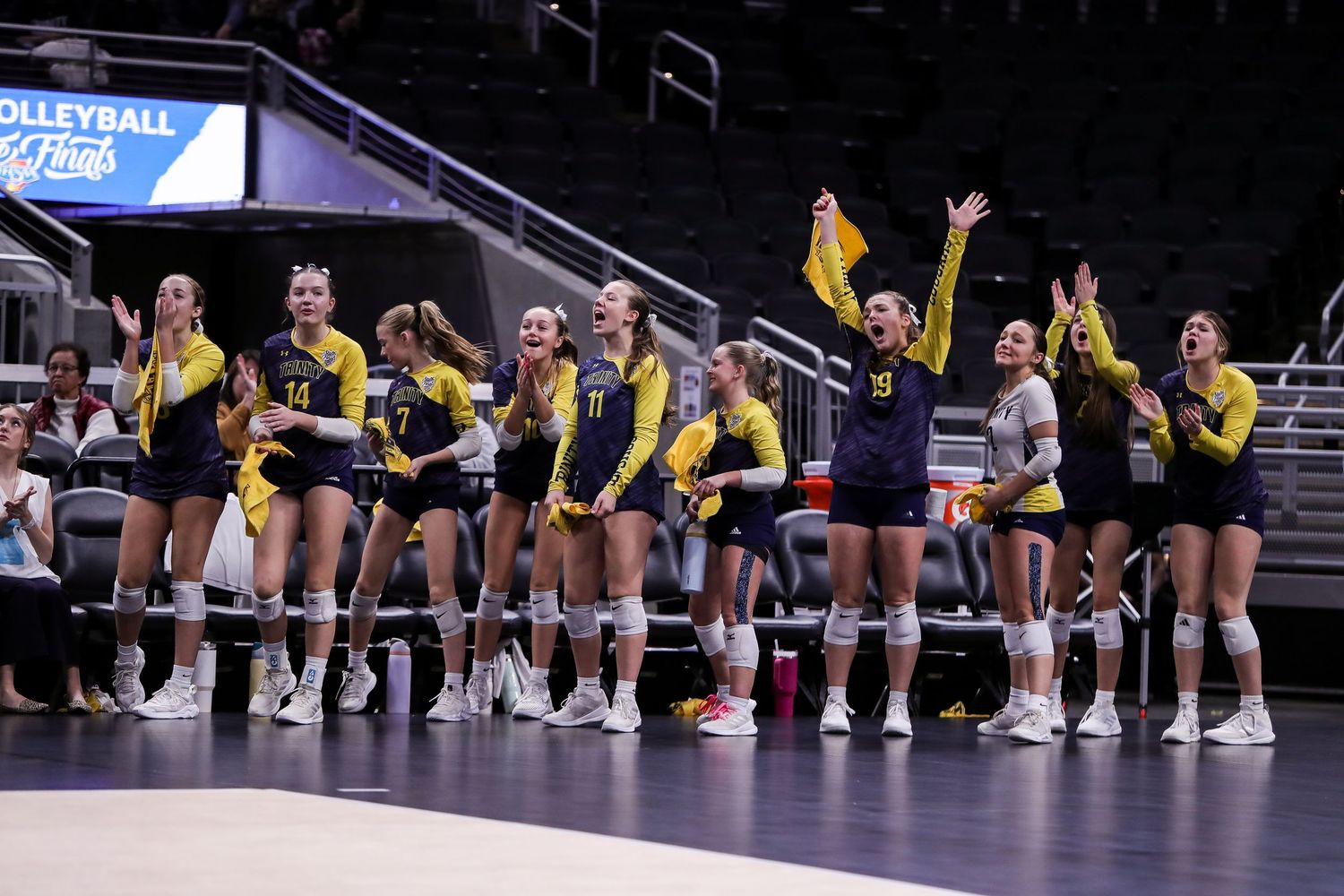 volleyball players line up on the court during pre-game introductions in their yellow and black uniforms.