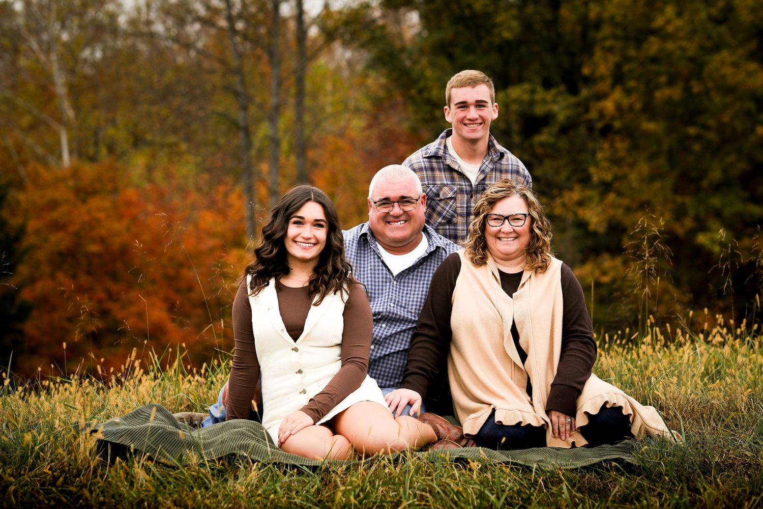 Group portrait session outdoors during autumn with golden foliage and natural lighting in the background.