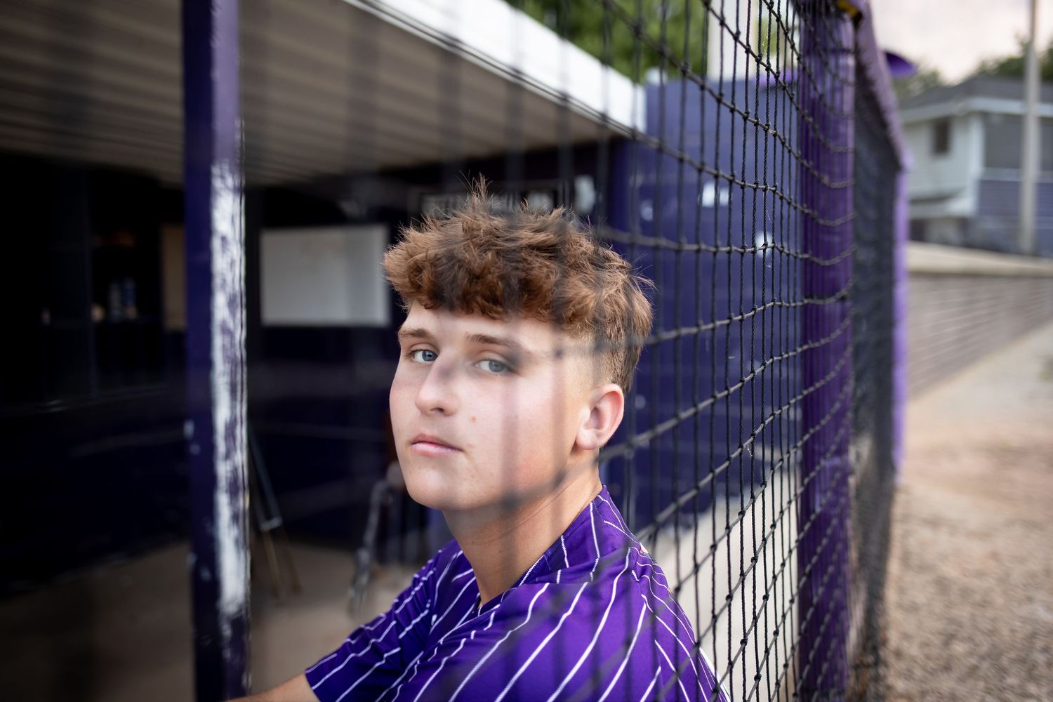 Person in purple striped shirt poses against chain link fence in multiple similar outdoor shots.
