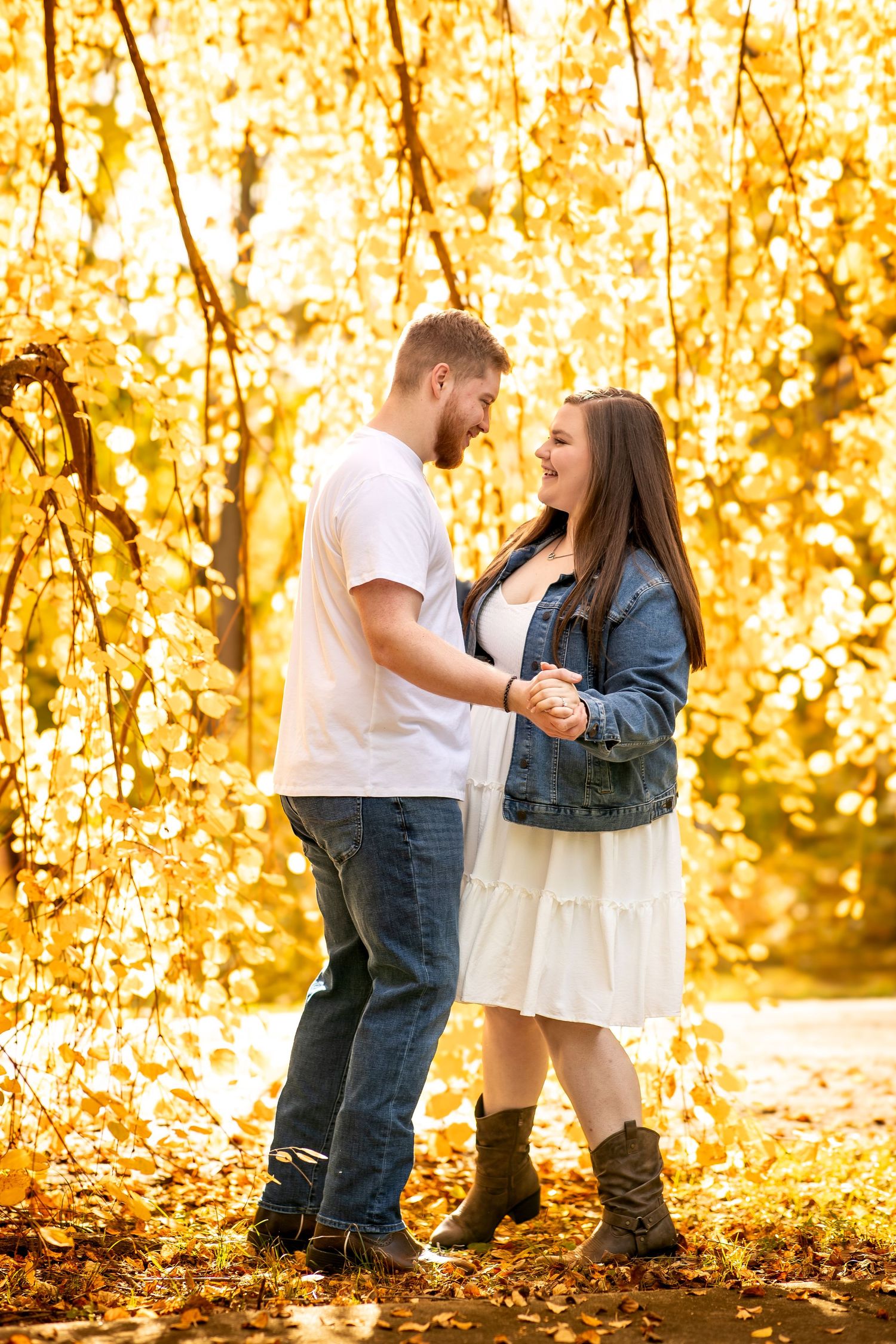Couple embraces in autumn forest with golden yellow leaves creating a warm romantic atmosphere.
