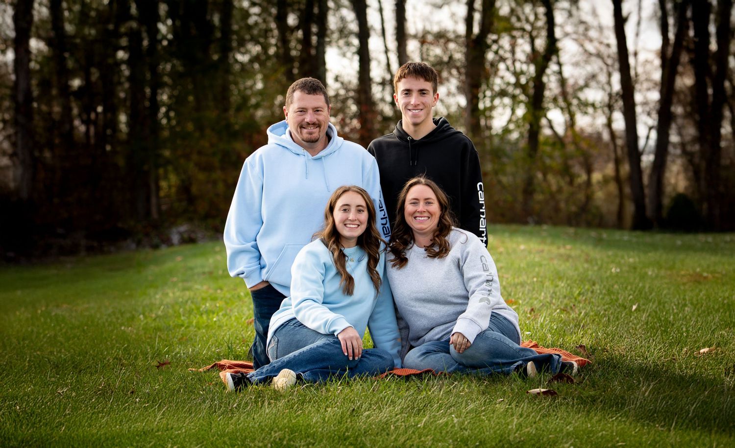 A family sits together on grassy slopes during an outdoor autumn photo session in nature.