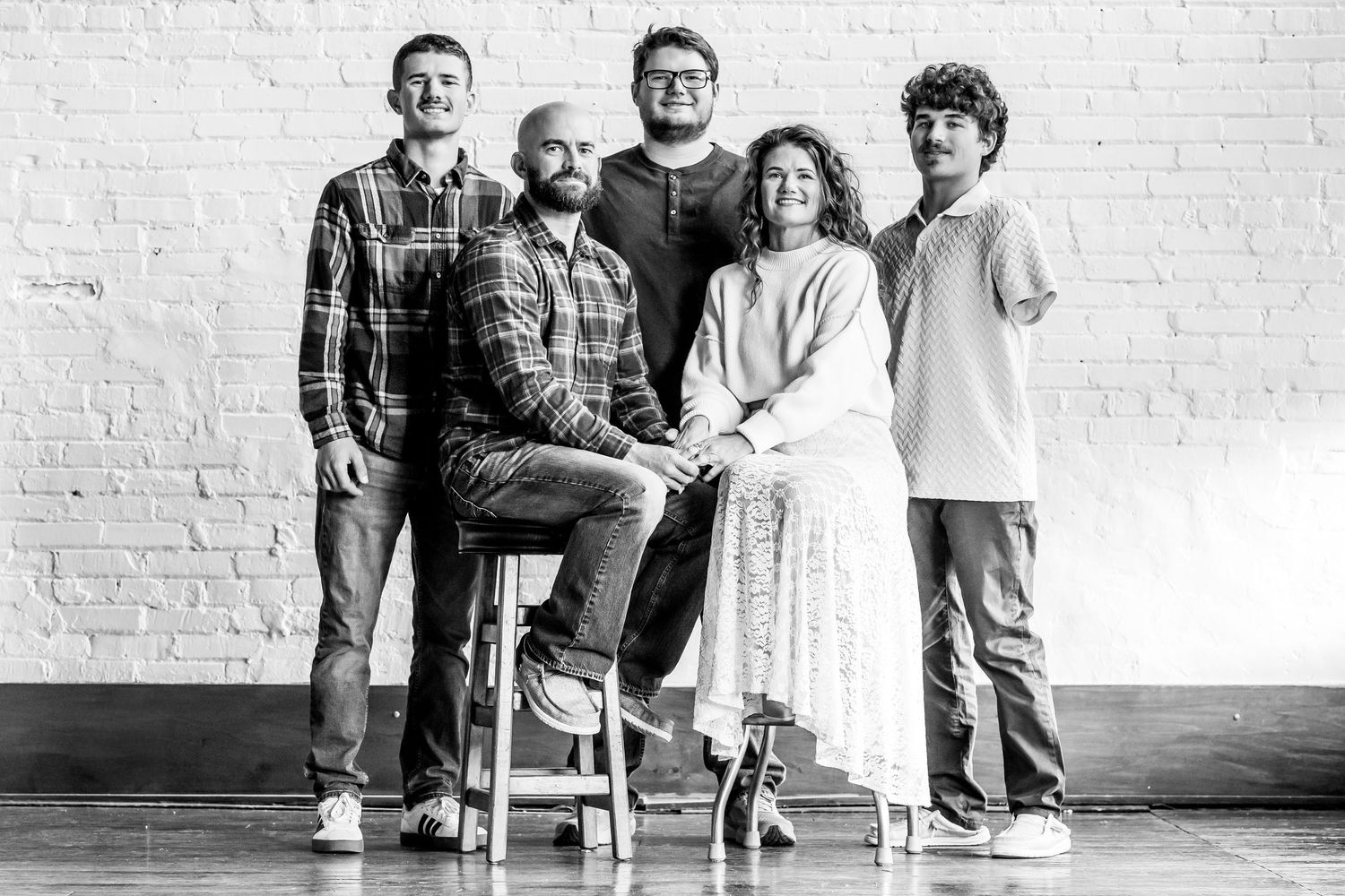 A series of black and white photos showing a family posing together against a white brick wall background.