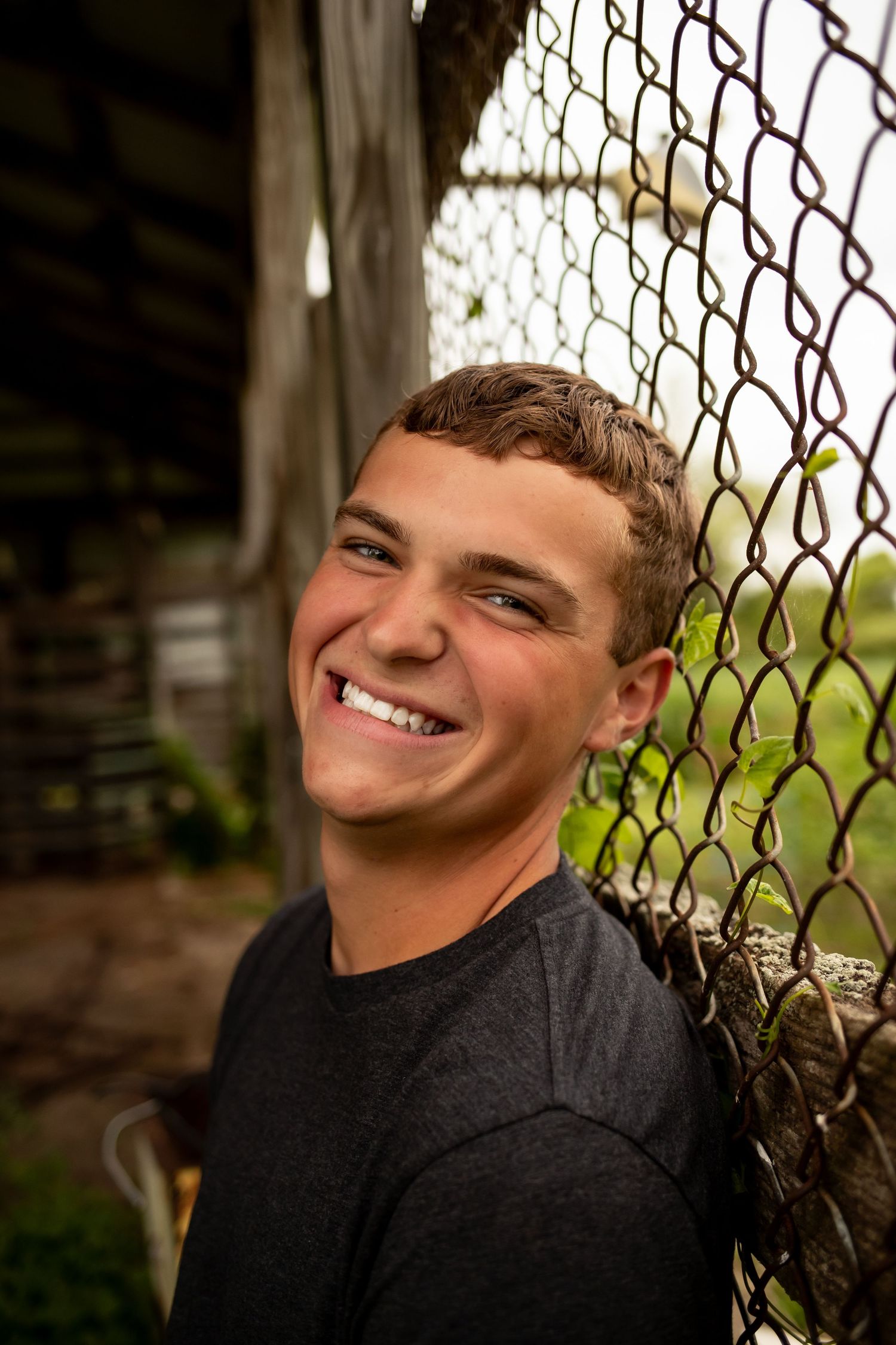 Portrait series showing candid expressions and genuine smiles against a chain link fence background in natural light.