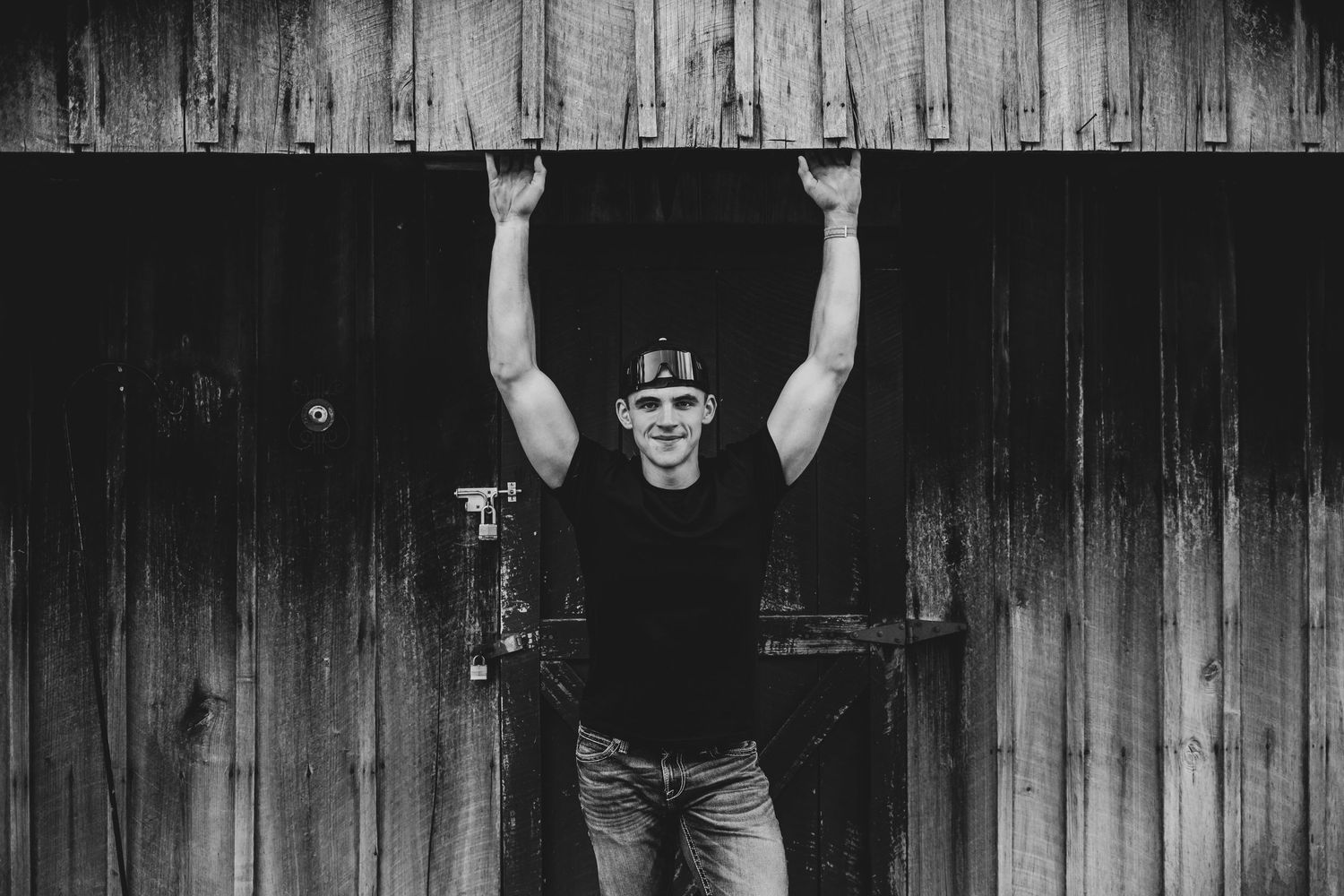 A black and white photo series showing someone in casual attire posing against a rustic wooden wall background.