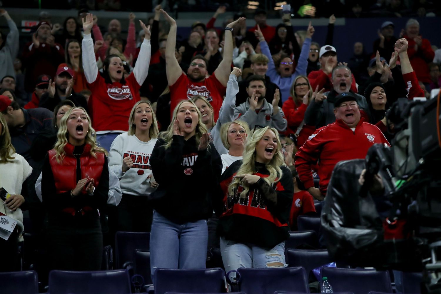 Football fans in stadium seats celebrate and cheer during an exciting game moment.