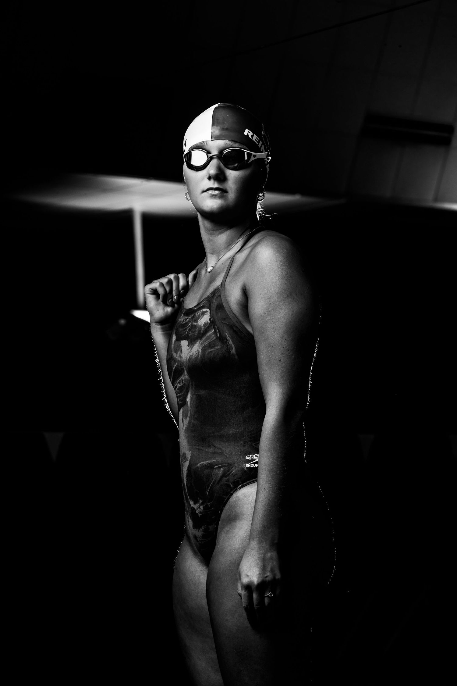 Black and white artistic photographs show a competitive swimmer in dramatic lighting wearing goggles and swim cap.
