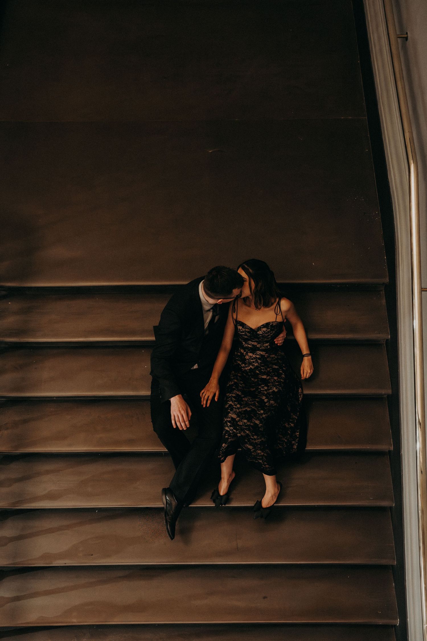 A series of moody photographs showing two figures sitting on dark wooden stairs.