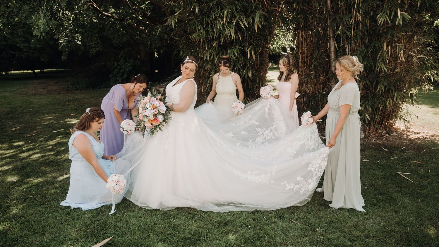 Wedding party relaxing on grass during an outdoor celebration.