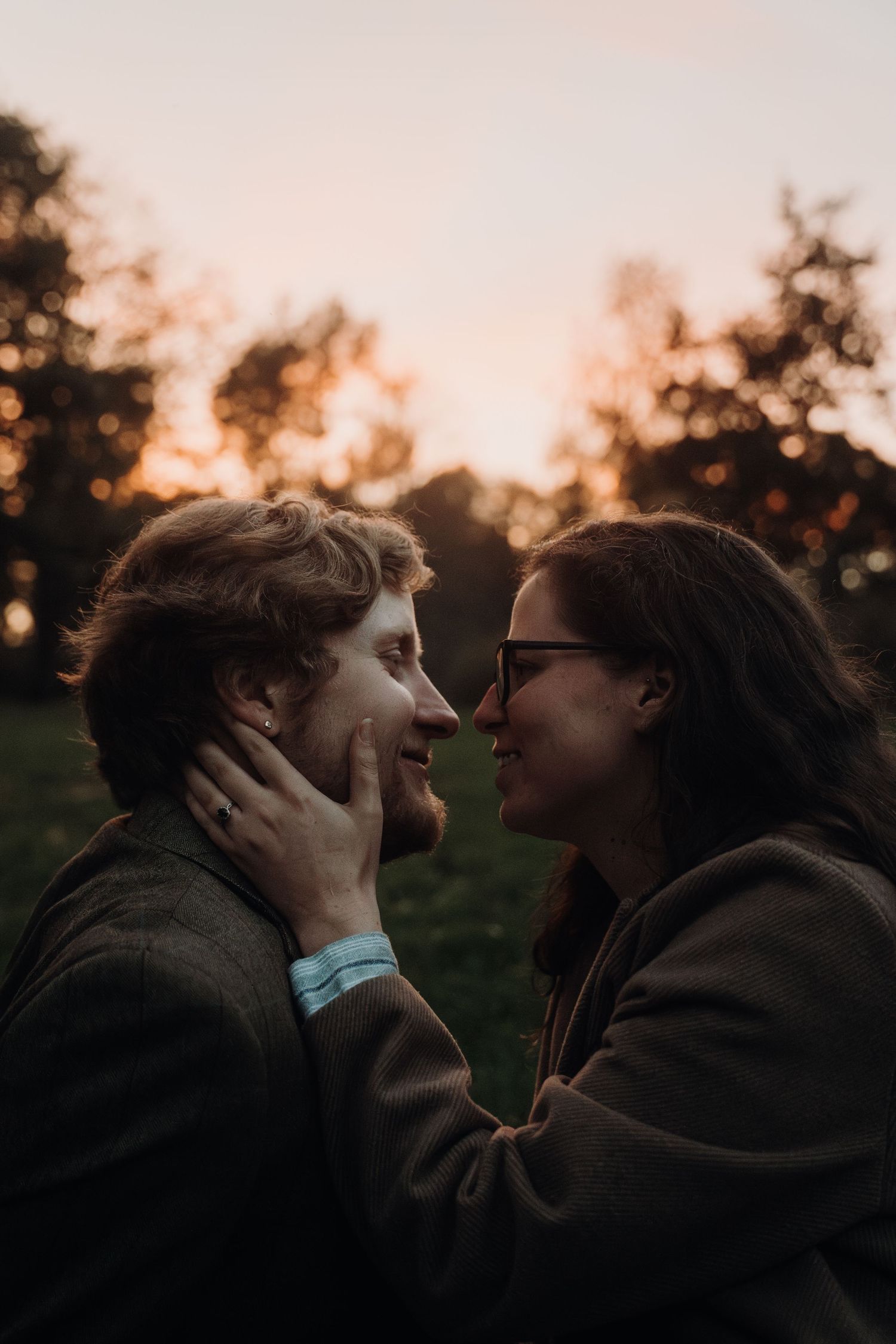Silhouetted couple embracing and kissing during golden hour outdoors.