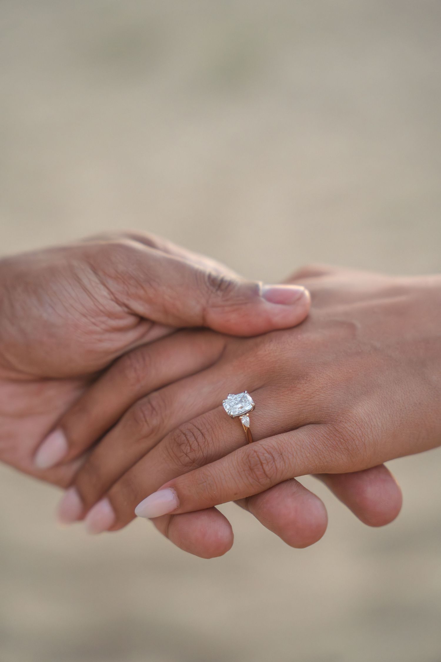 Close-up of hands with engagement ring showing tender moment between couple.