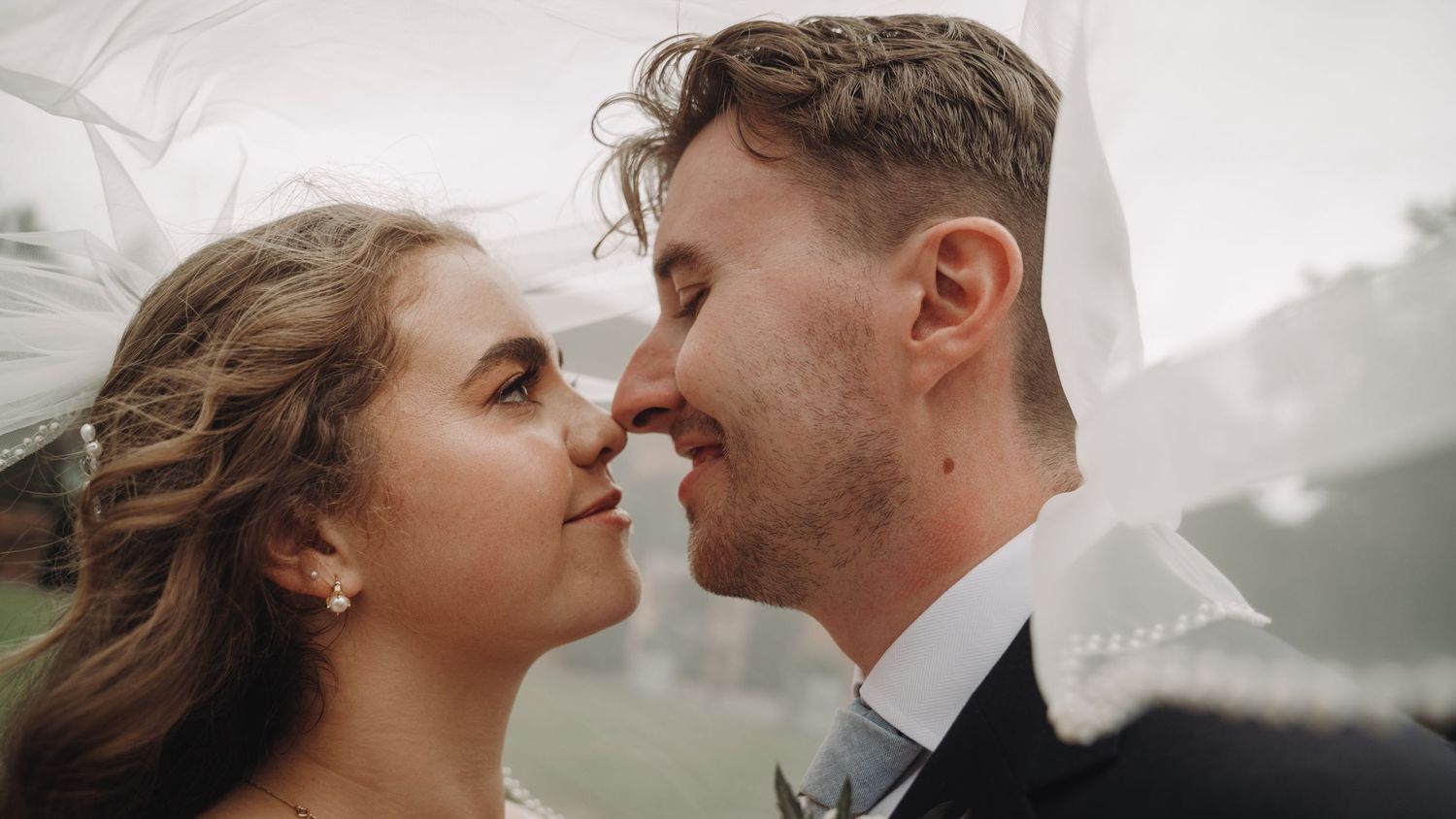 Intimate close-up of newlyweds sharing a romantic moment against misty background.