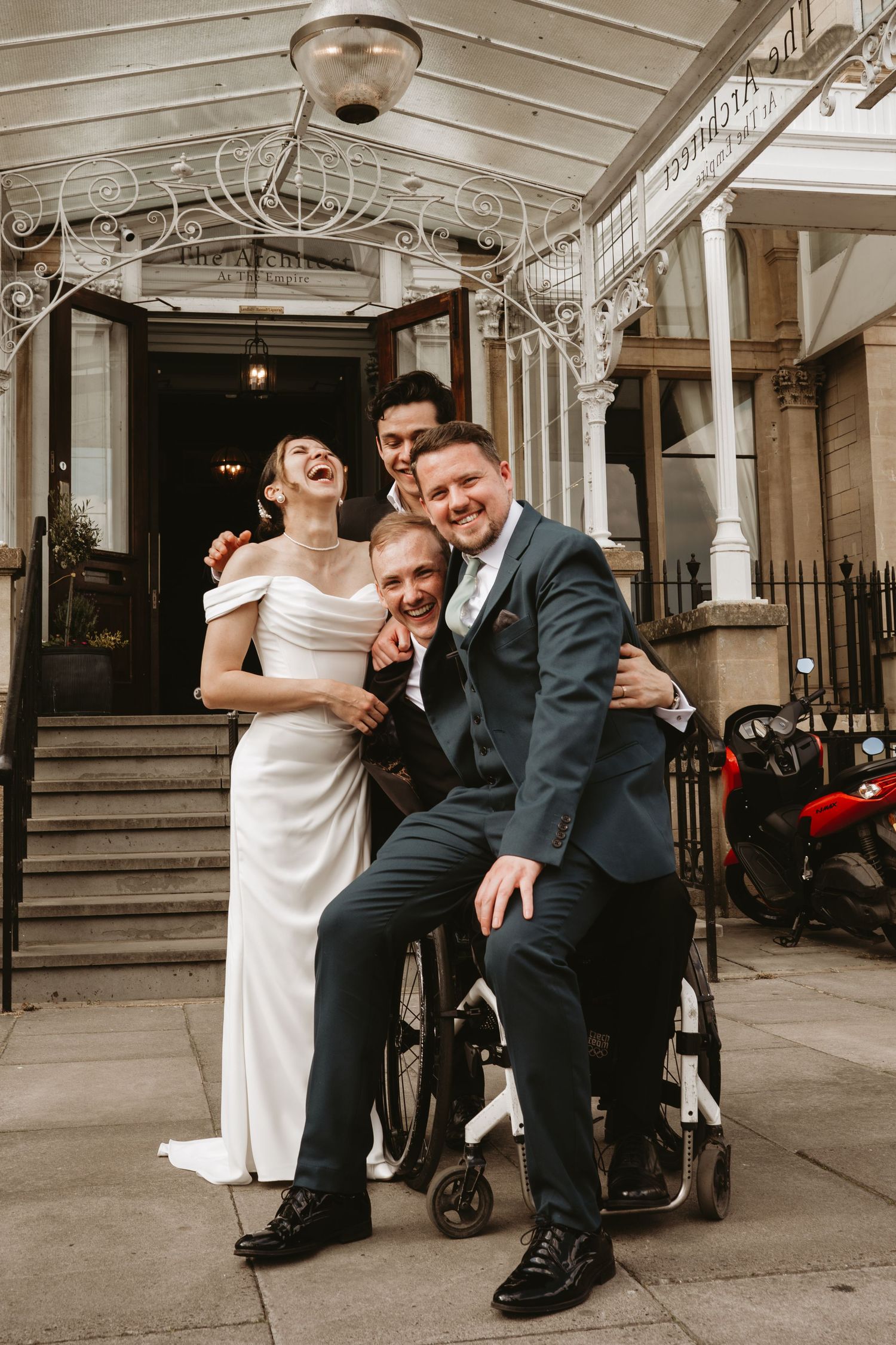 Playful wedding moment captured on vintage building steps with ornate white railings.