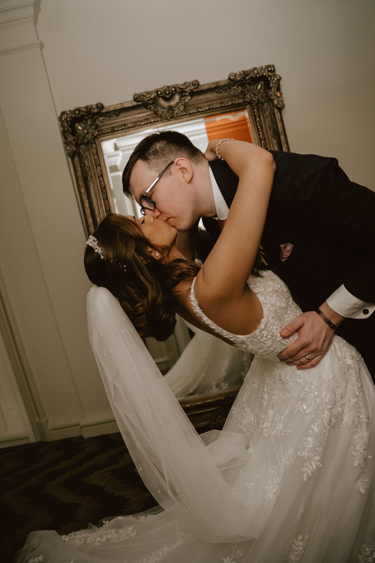 A romantic wedding moment captured as a couple shares an intimate kiss in formal attire.