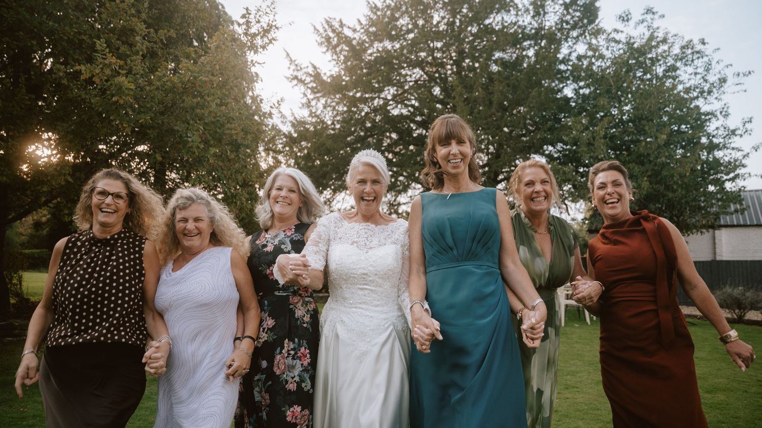 Group of wedding guests celebrate together outdoors at sunset.