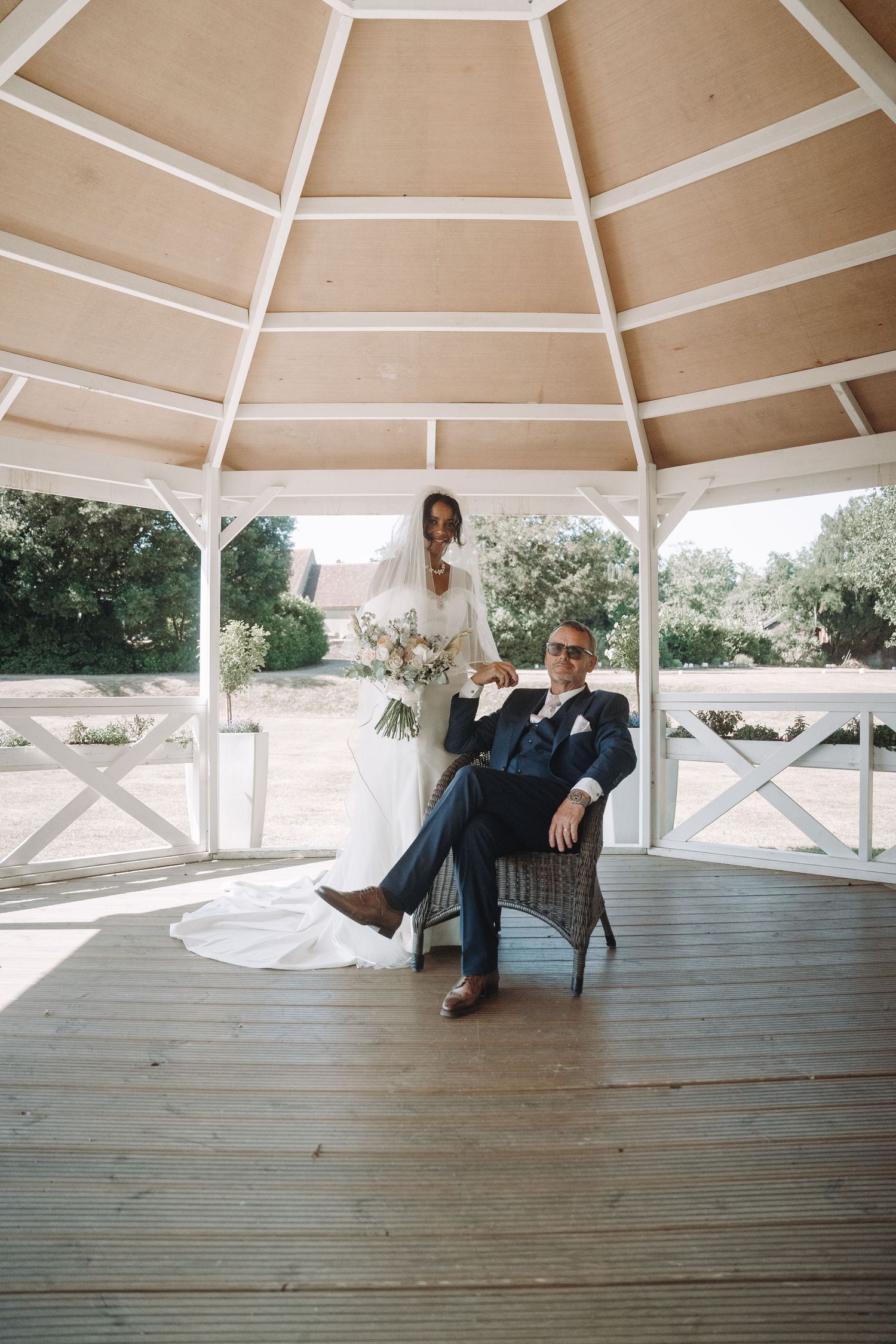 Romantic couple moment captured in white wooden gazebo with geometric ceiling.