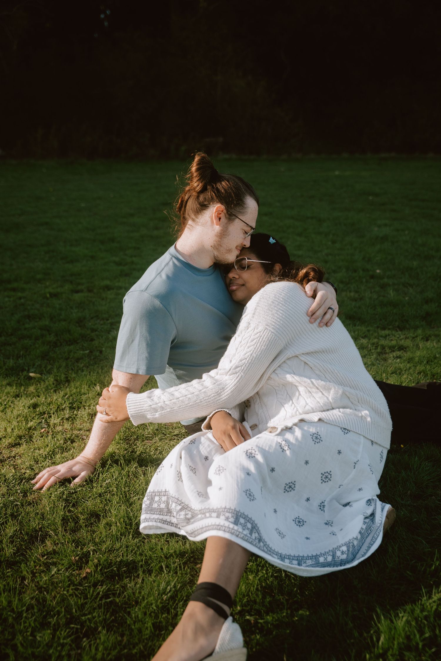 Intimate couple portrait on grass in soft evening light.