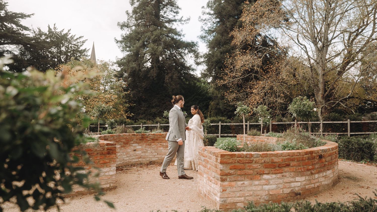 A panoramic view of a garden wedding venue with brick walls and trees.