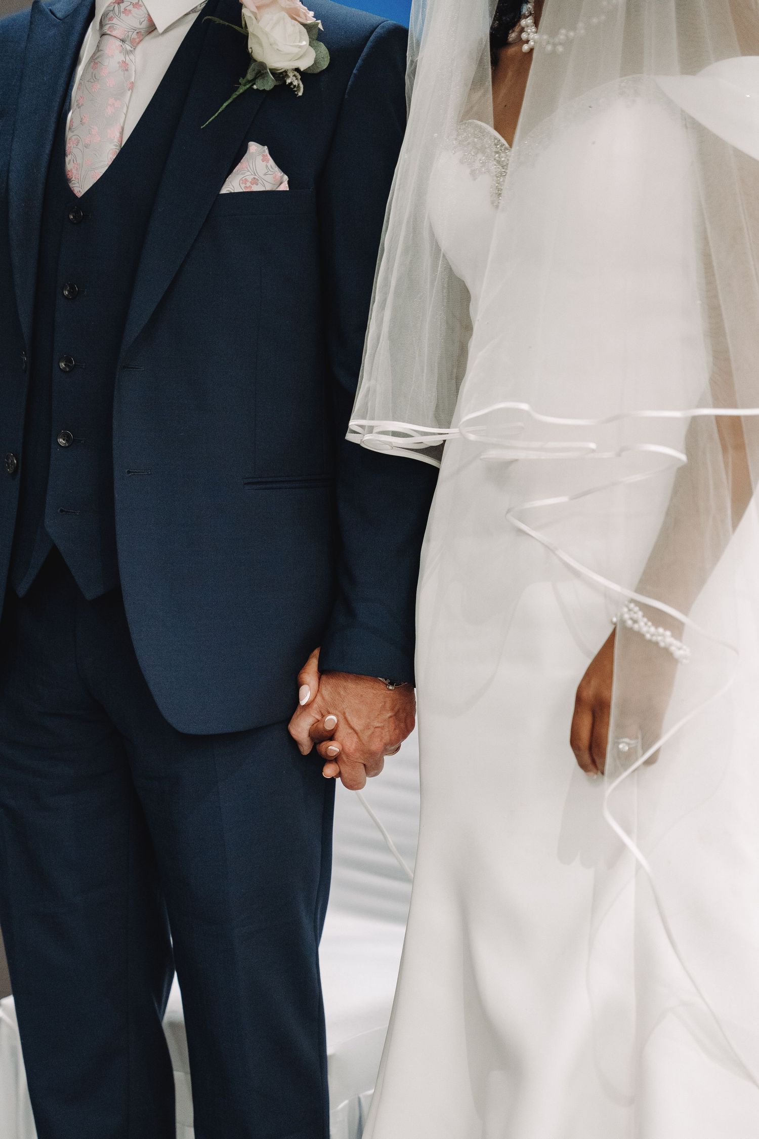 Formal wedding attire detail showing navy suit and white dress.