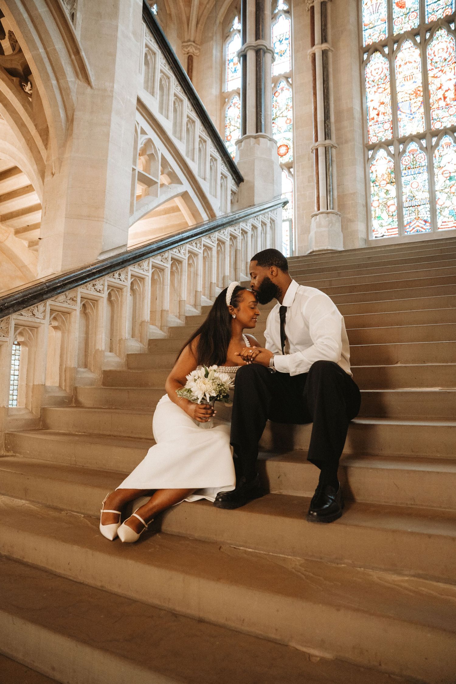 Romantic wedding couple shares intimate moments while sitting on grand marble staircase in historic church setting.