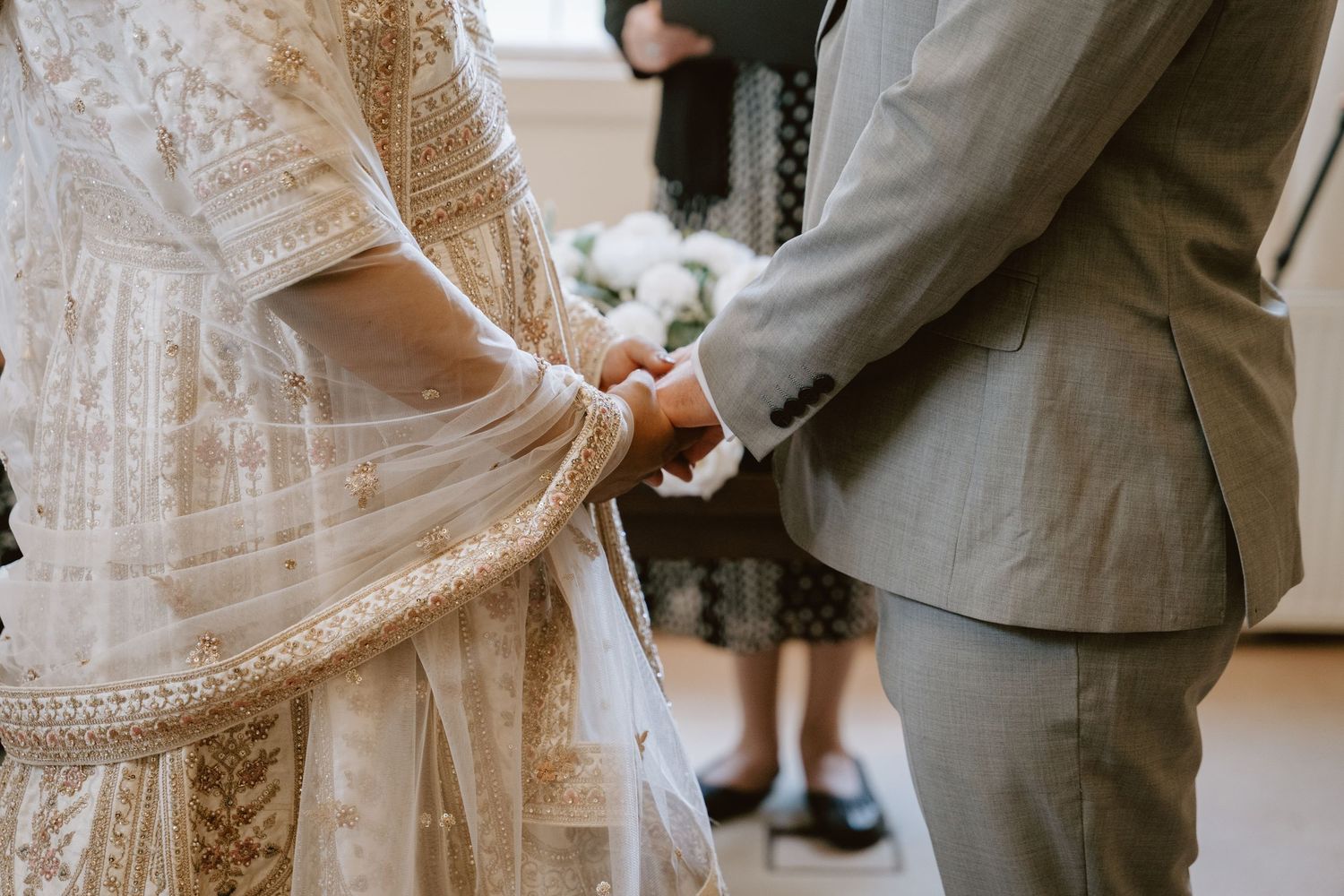 Intimate wedding detail shot focusing on intricate lace dress and formal attire.