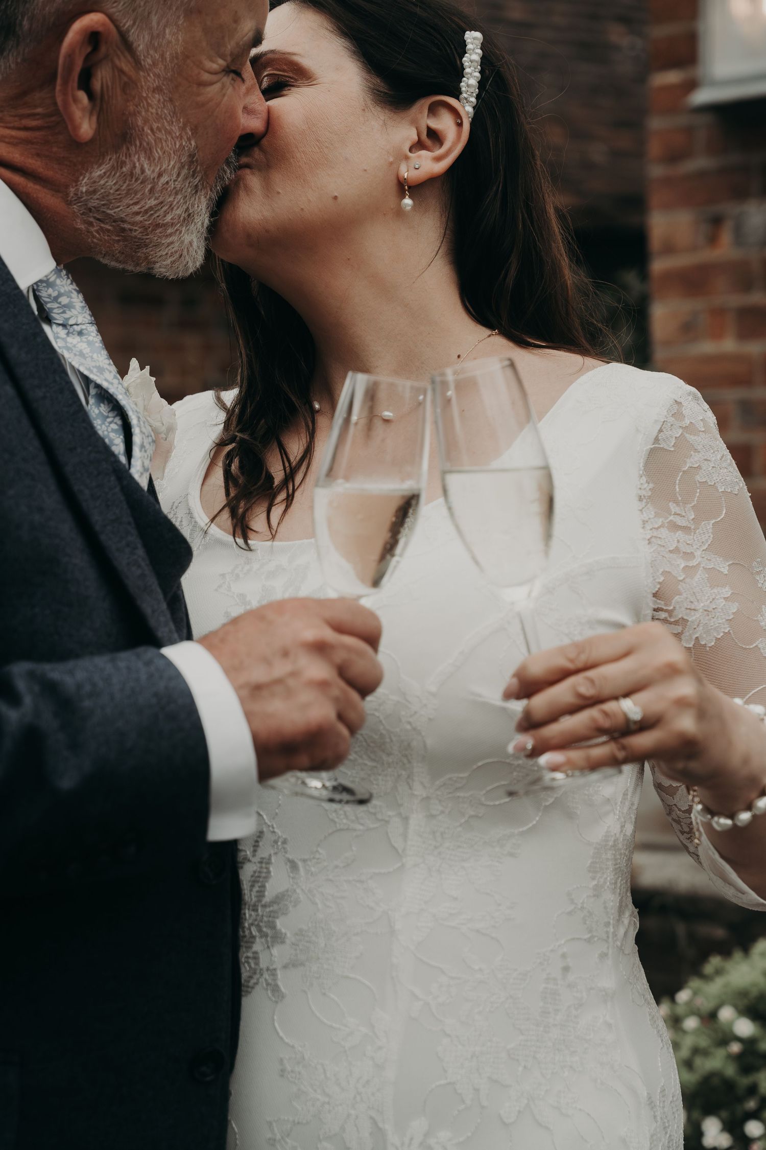 A tender moment between a couple sharing champagne in elegant wedding attire.