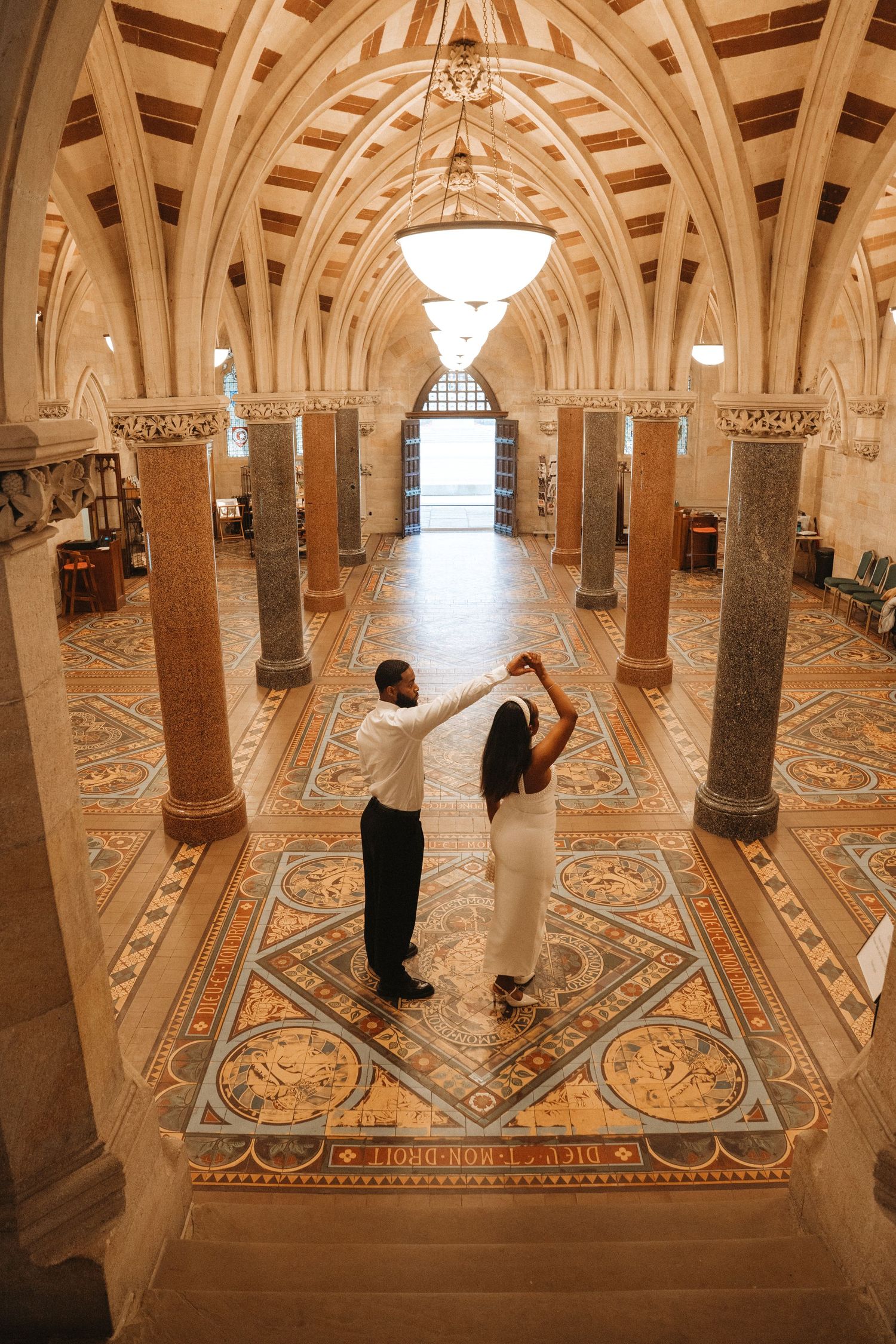 Interior view of an ornate crypt with vaulted arches and intricate mosaic floor patterns in warm beige tones.