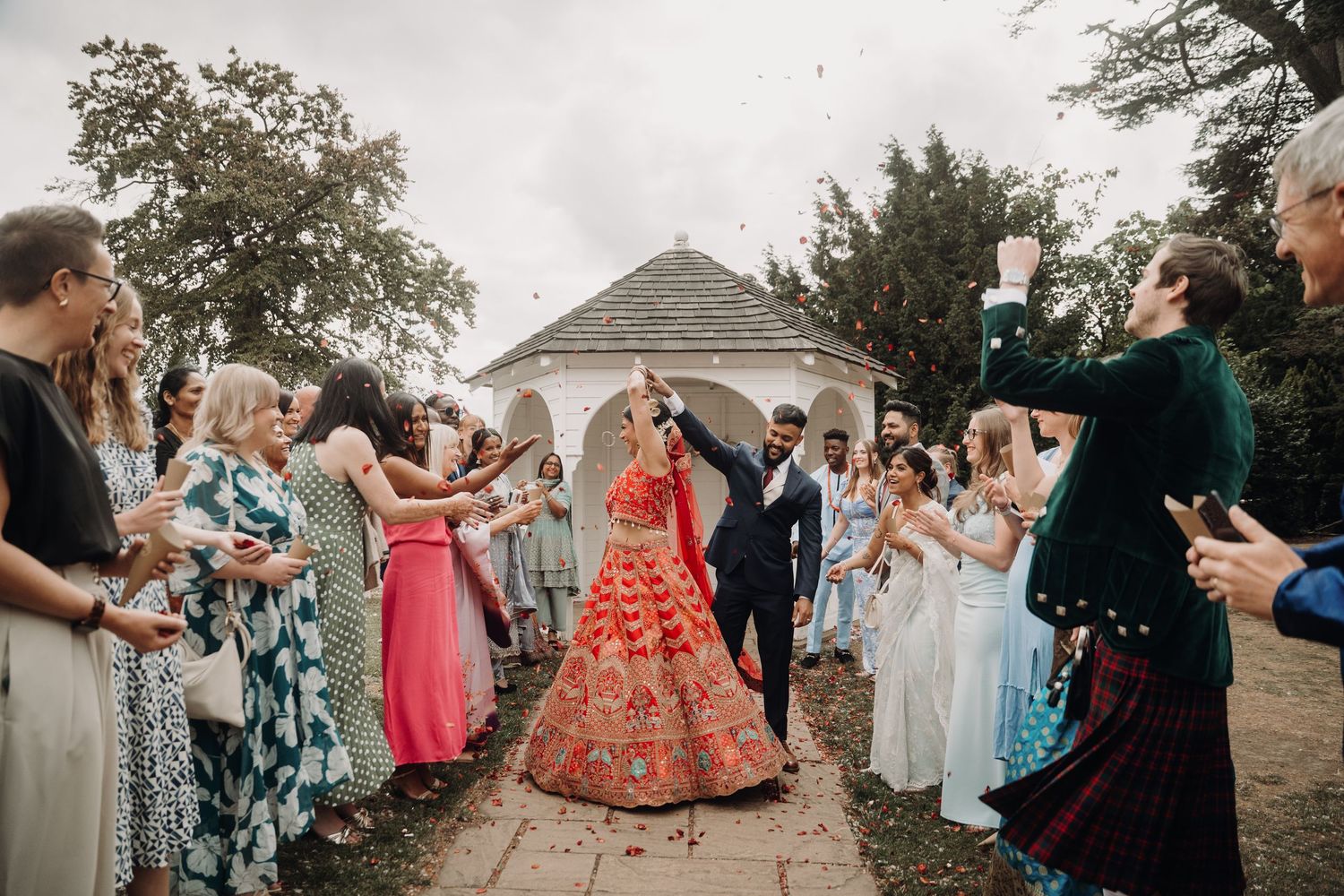 Wedding guests in colorful dresses gathered outdoors for celebration.